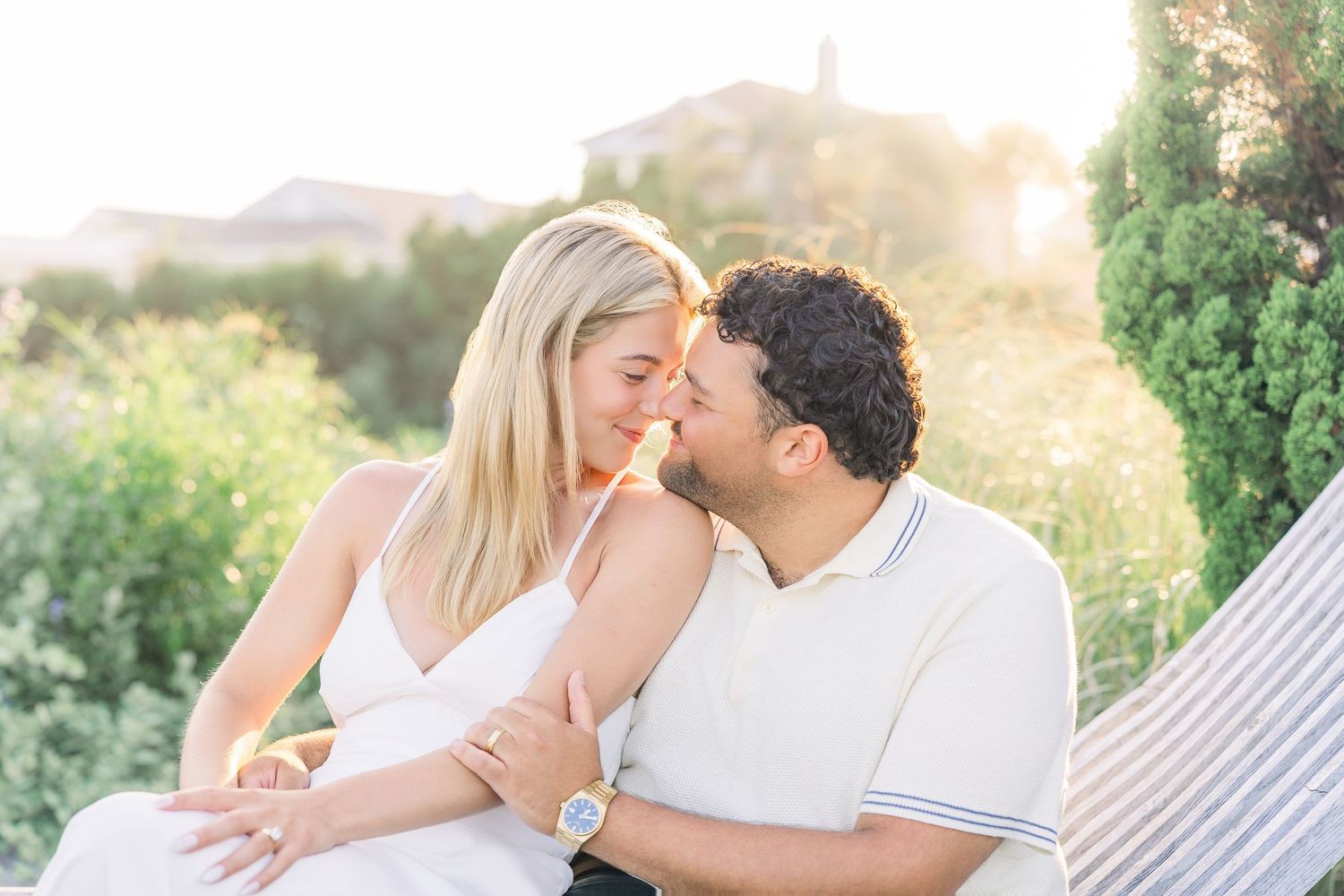 Couple sharing a romantic moment on a hammock at golden hour with lush greenery and warm sunlight.