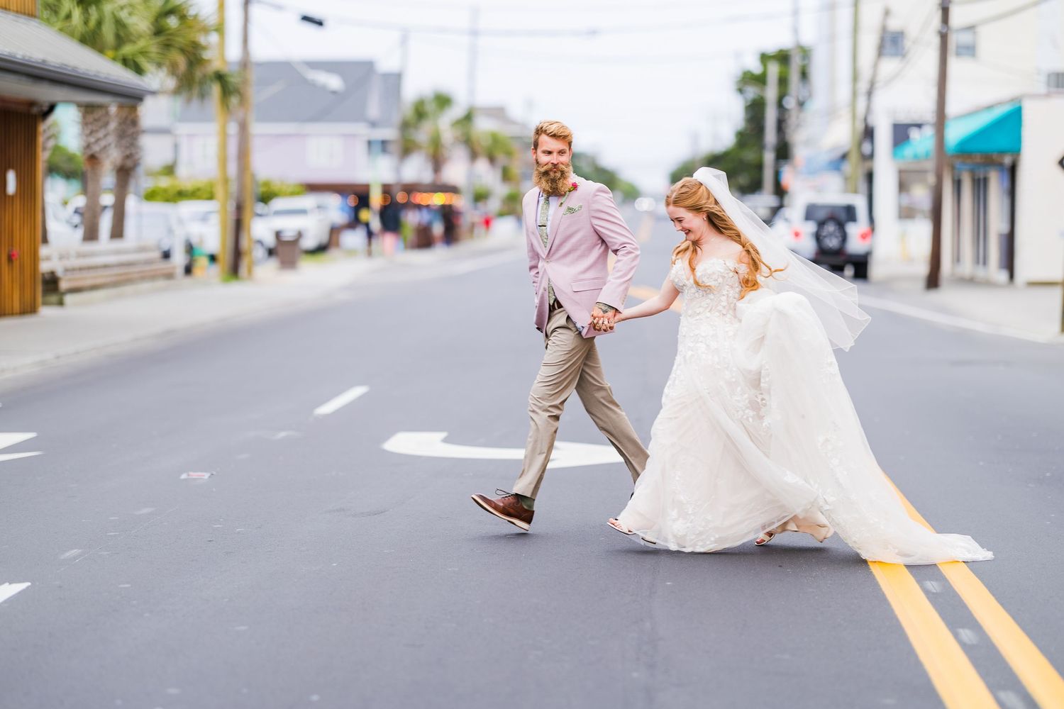 Playful wedding couple running and dancing in the middle of a city street in Wrightsville Beach, nc