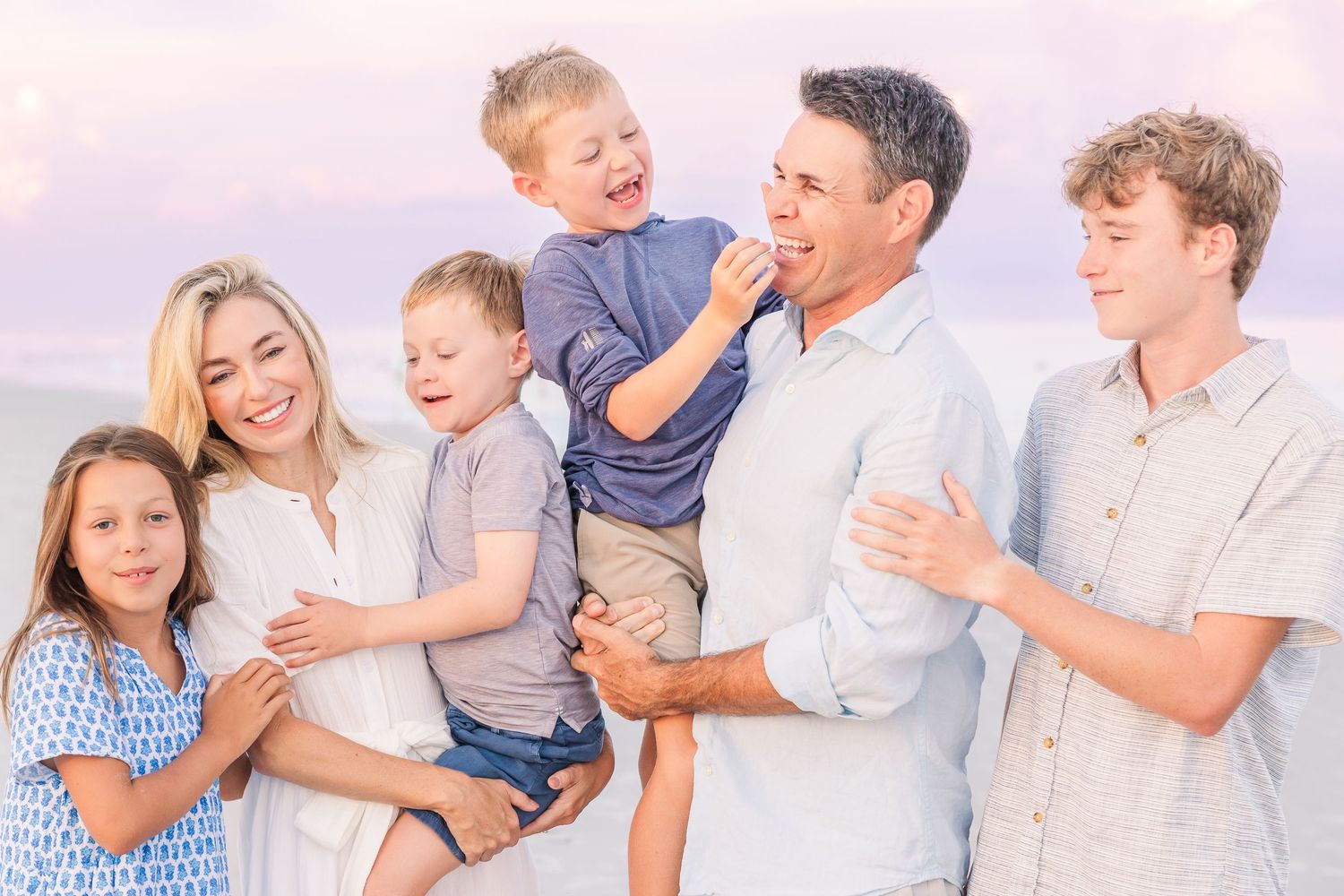 Casual family beach photo with everyone laughing and smiling together.