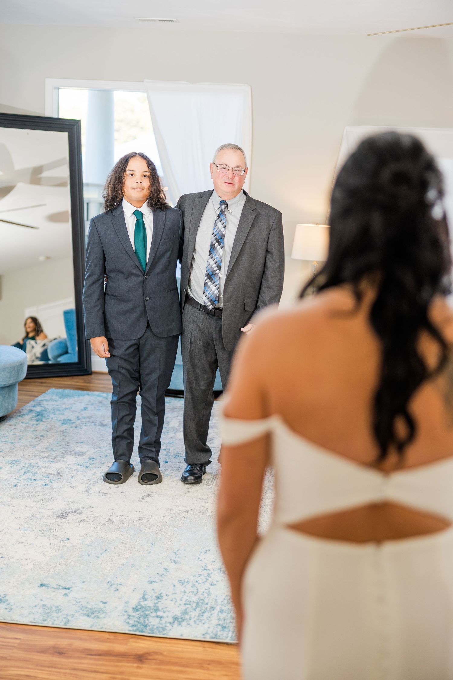 Wedding first look with guests in formal attire standing in a bright modern room wedding groom bride lake Gaston photographer light airy