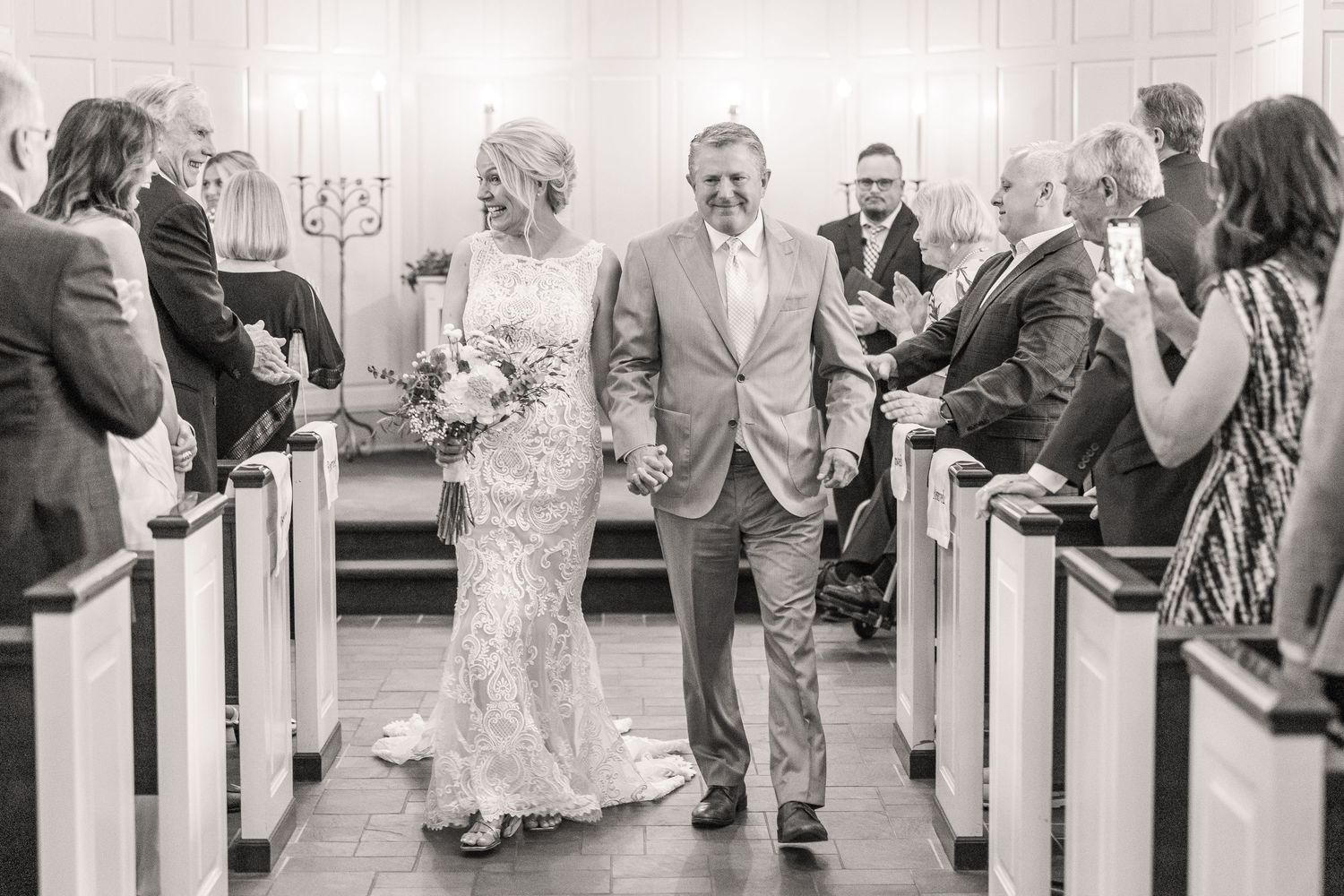 Wedding ceremony processional in church with white walls and red carpet aisle.