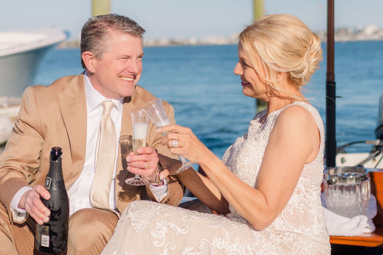 A couple sharing champagne on a boat dock during a waterfront celebration.