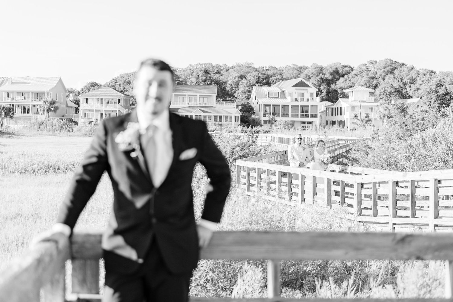 Wedding couple laughs together on a sunny boardwalk with coastal buildings in background southport elopement wedding bride groom light airy