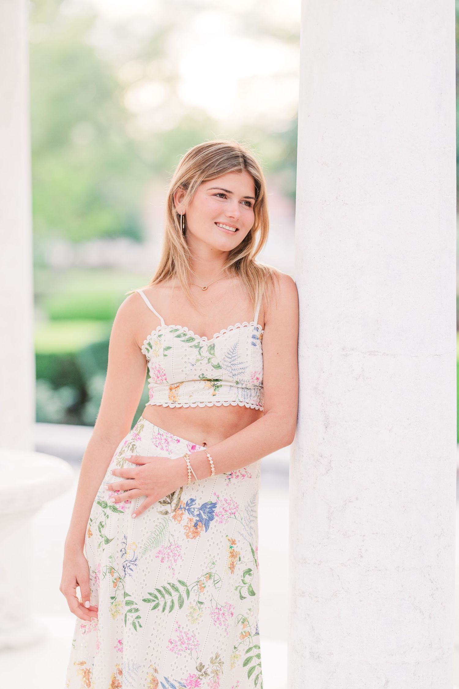 Two-piece floral outfit with crop top and skirt photographed in white colonnade.