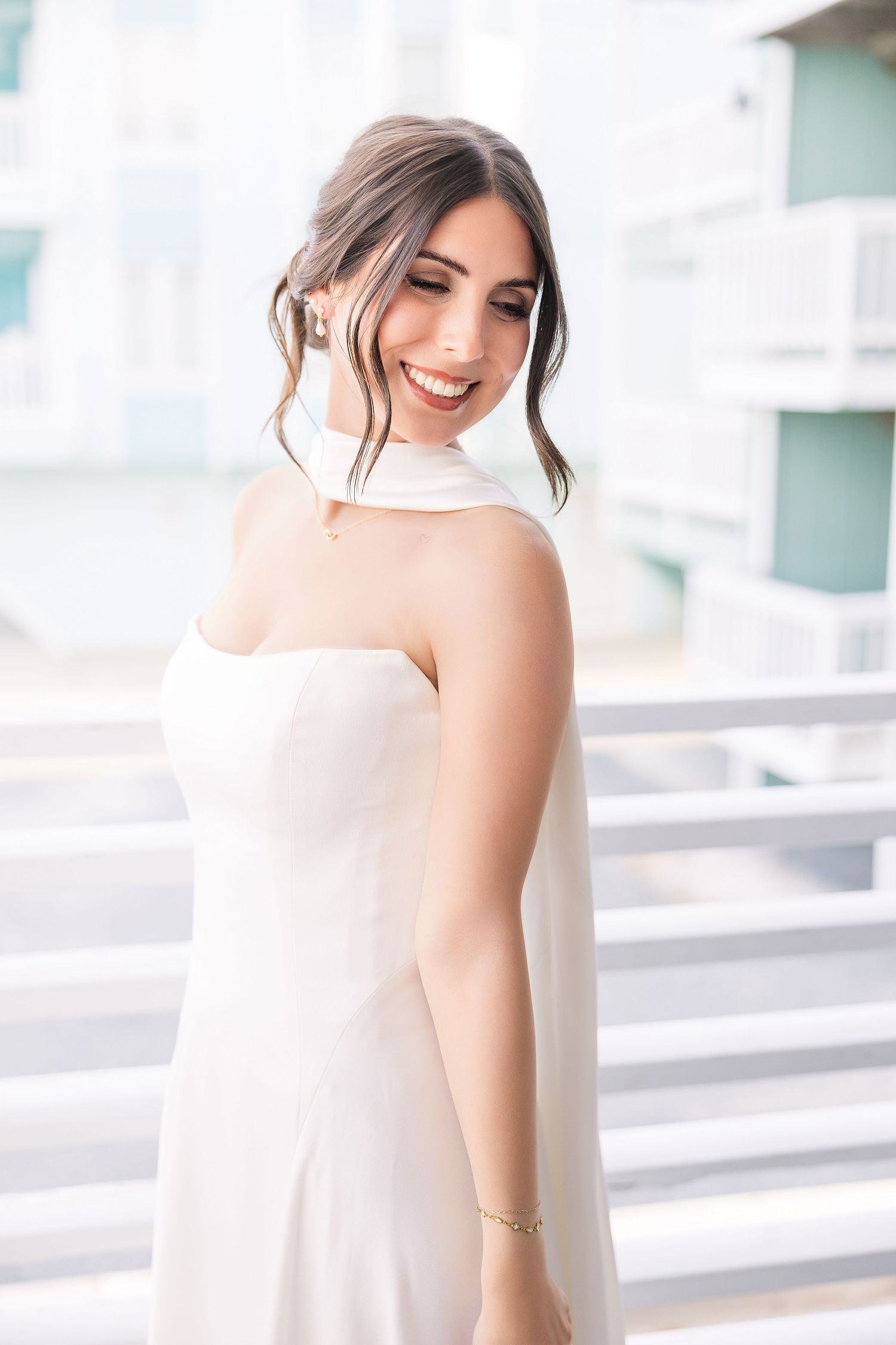 Smiling bride in a sleeveless white halter wedding dress with an elegant updo hairstyle outdoors in Carolina Beach near Wilmington, NC.