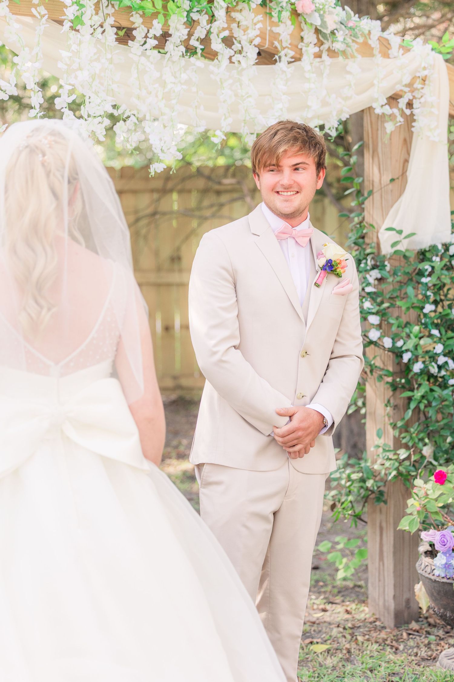 Couple shares a romantic moment under floral-covered garden arbor wedding groom bride wilmington photographer light and airy classic
