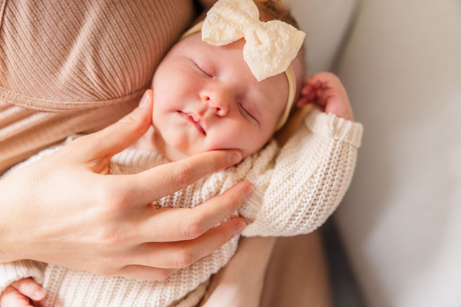 Newborn baby sleeping peacefully wrapped in cream knit blanket.