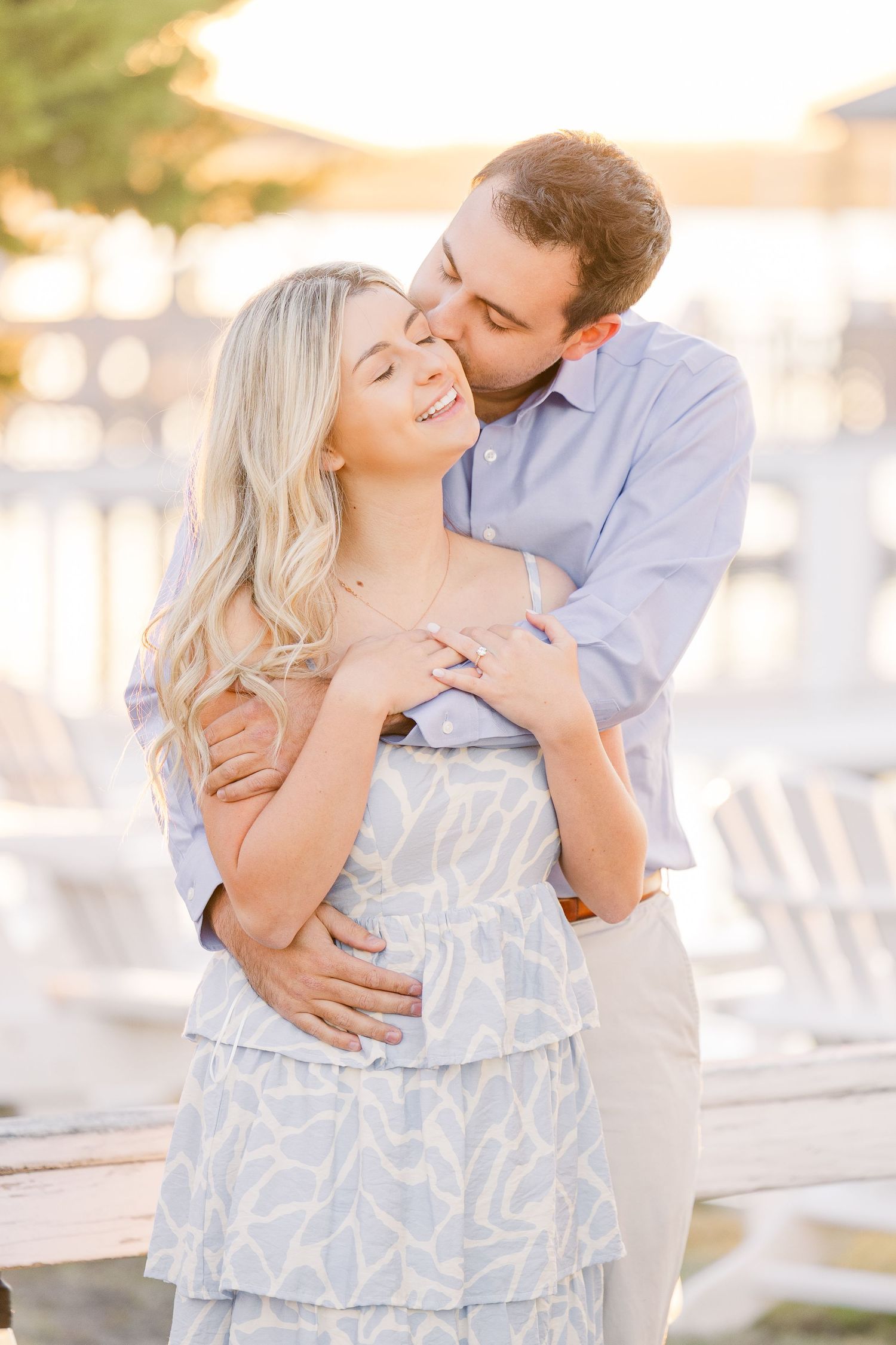 Sweet moment shared between couple on waterfront dock during golden hour.