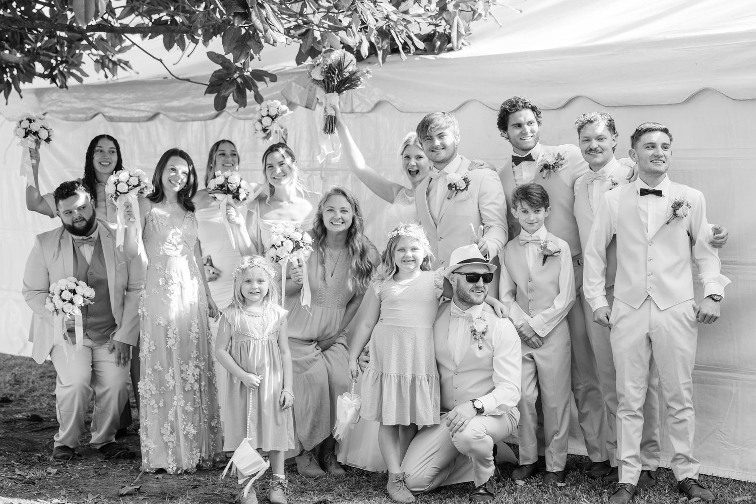 Black and white photo of wedding party posing together outdoors under a tent wedding groom bride wilmington photographer light and airy