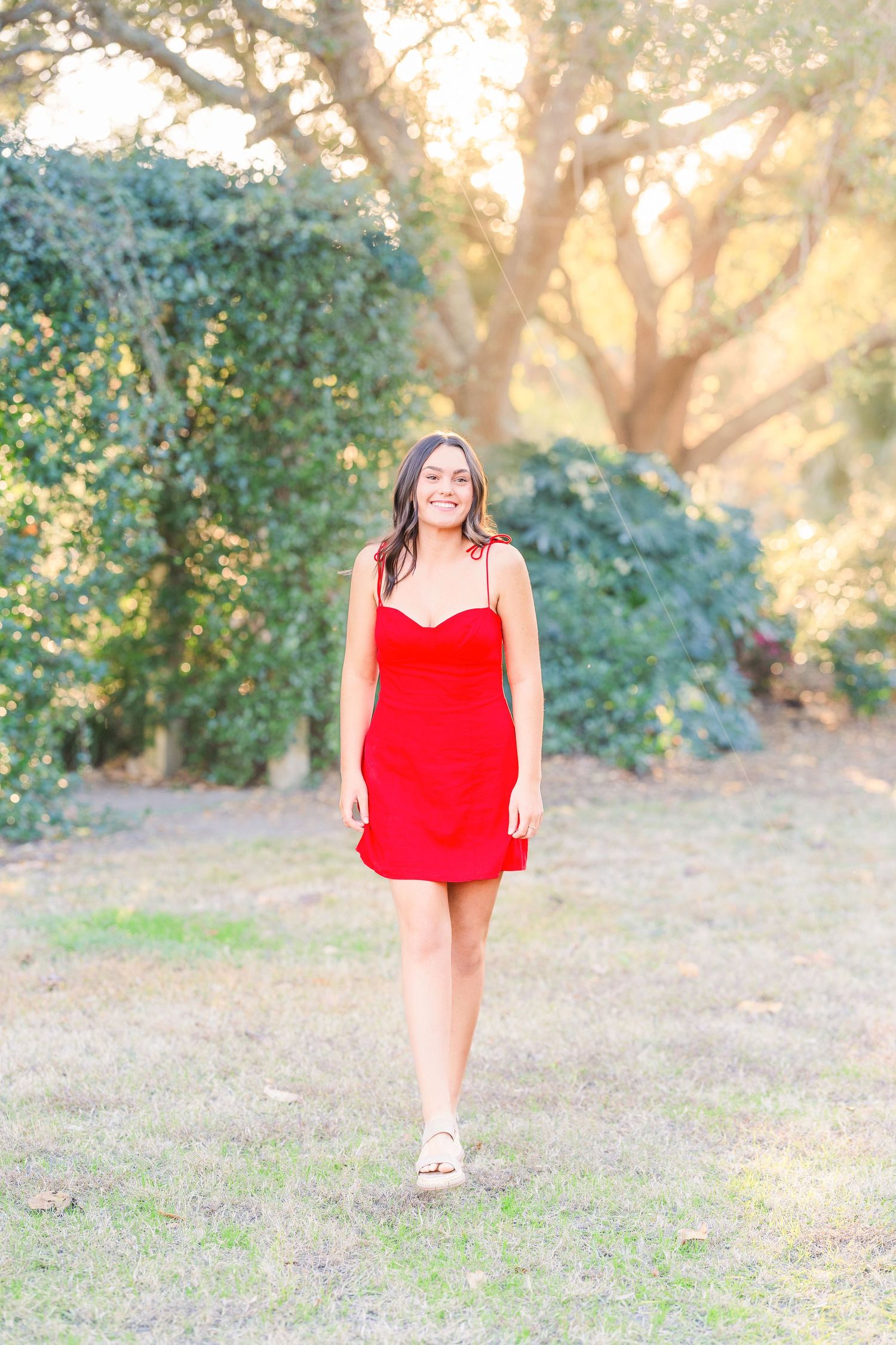 Outdoor photography session featuring a red dress in a sunlit wooded area.