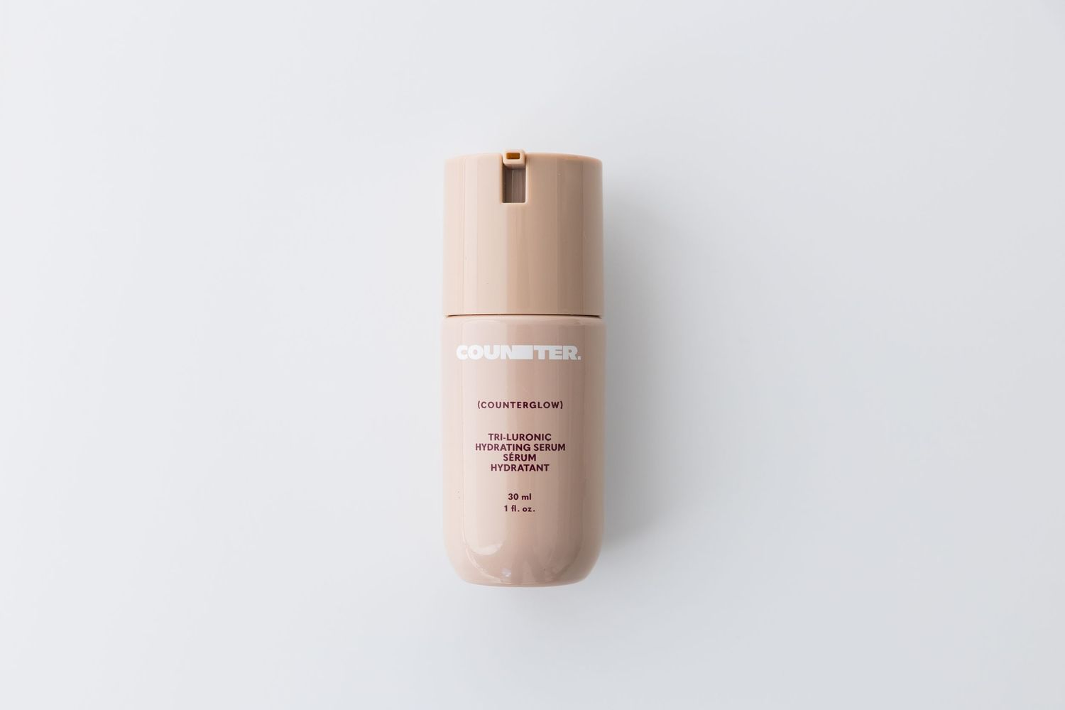 Beige colored beauty product bottle and packaging displayed on white surface.