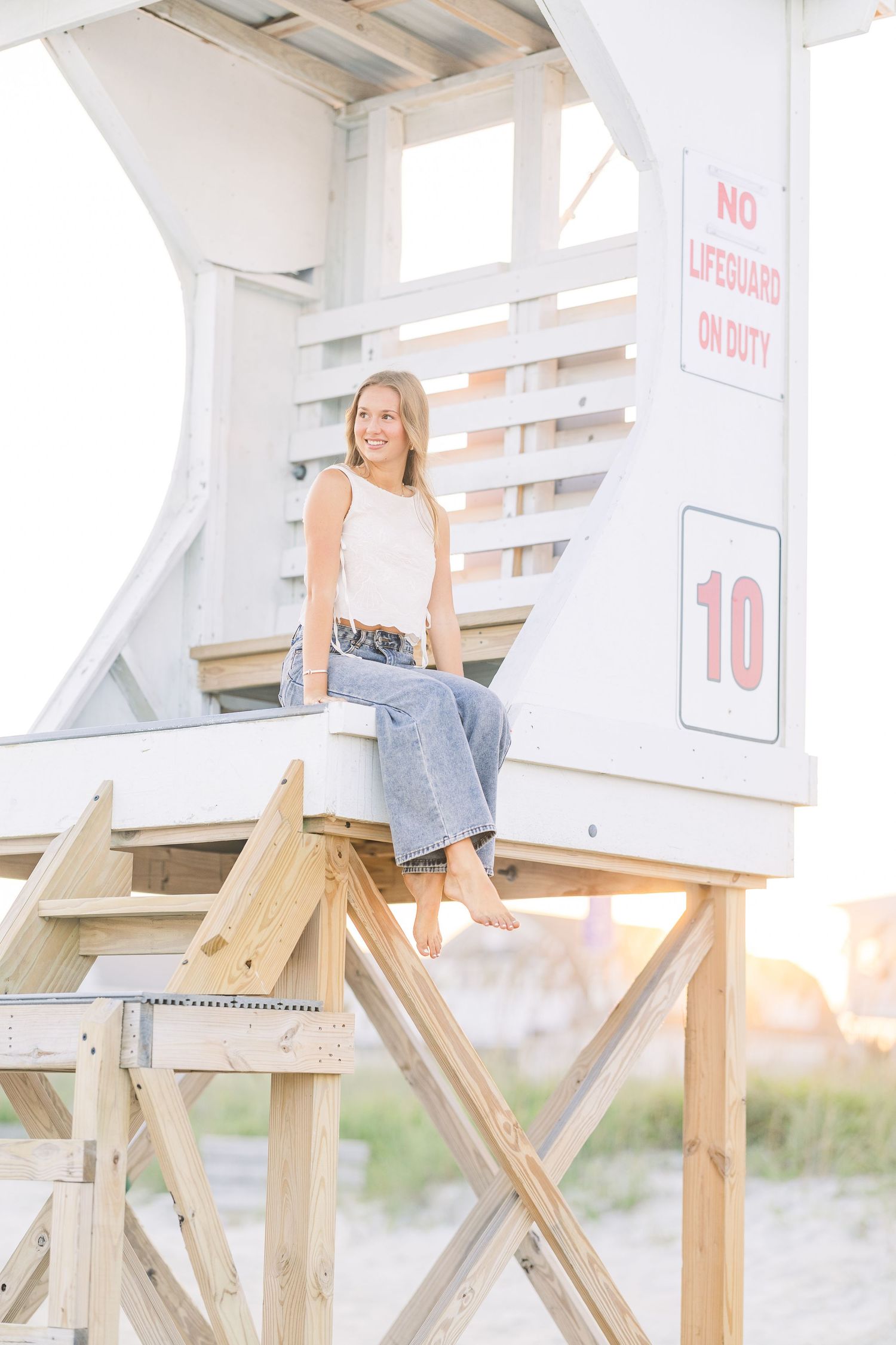 White wooden beach boardwalk stairs leading to sandy shore during golden hour.