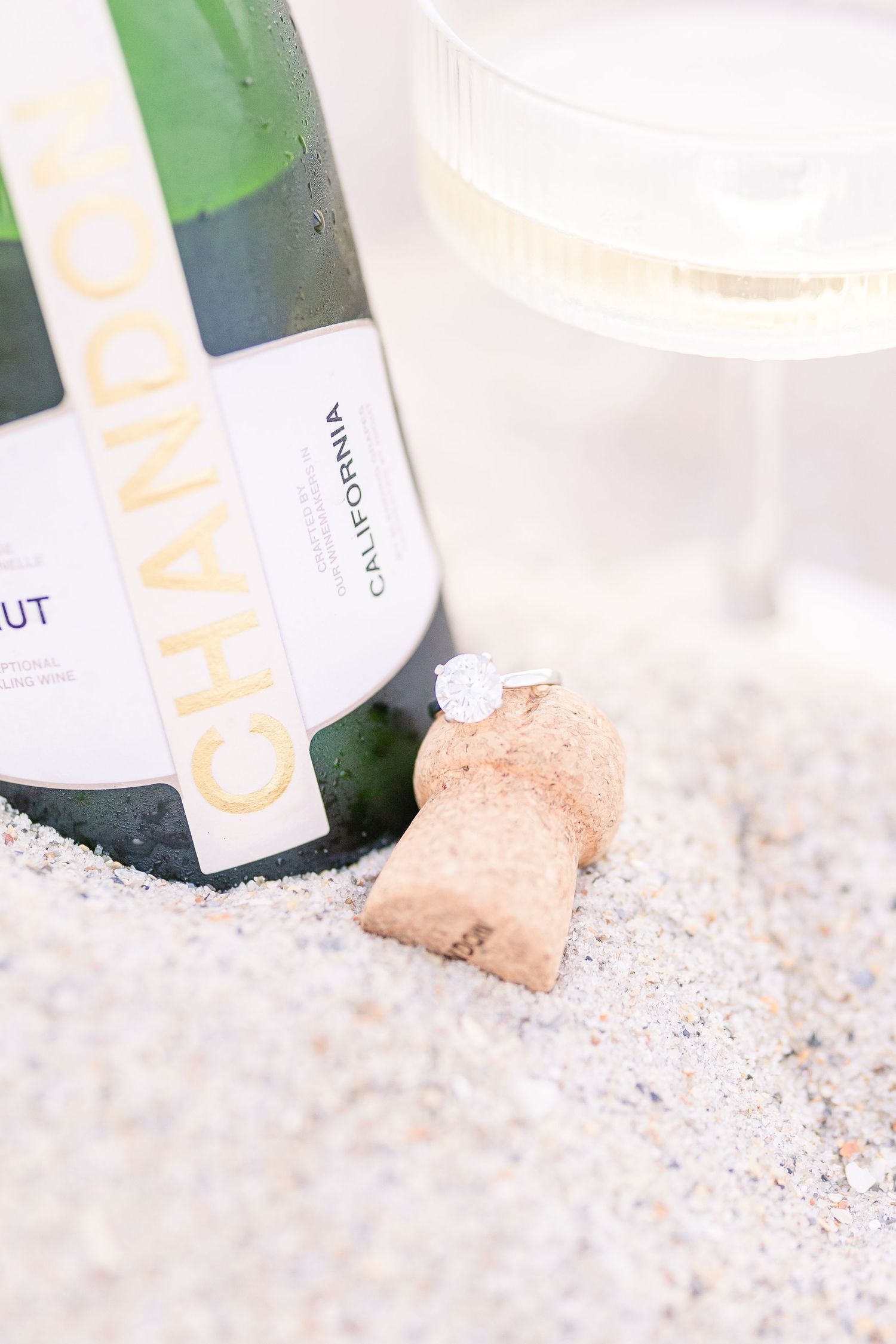 Champagne bottle nestled in white sand on a sunny beach.