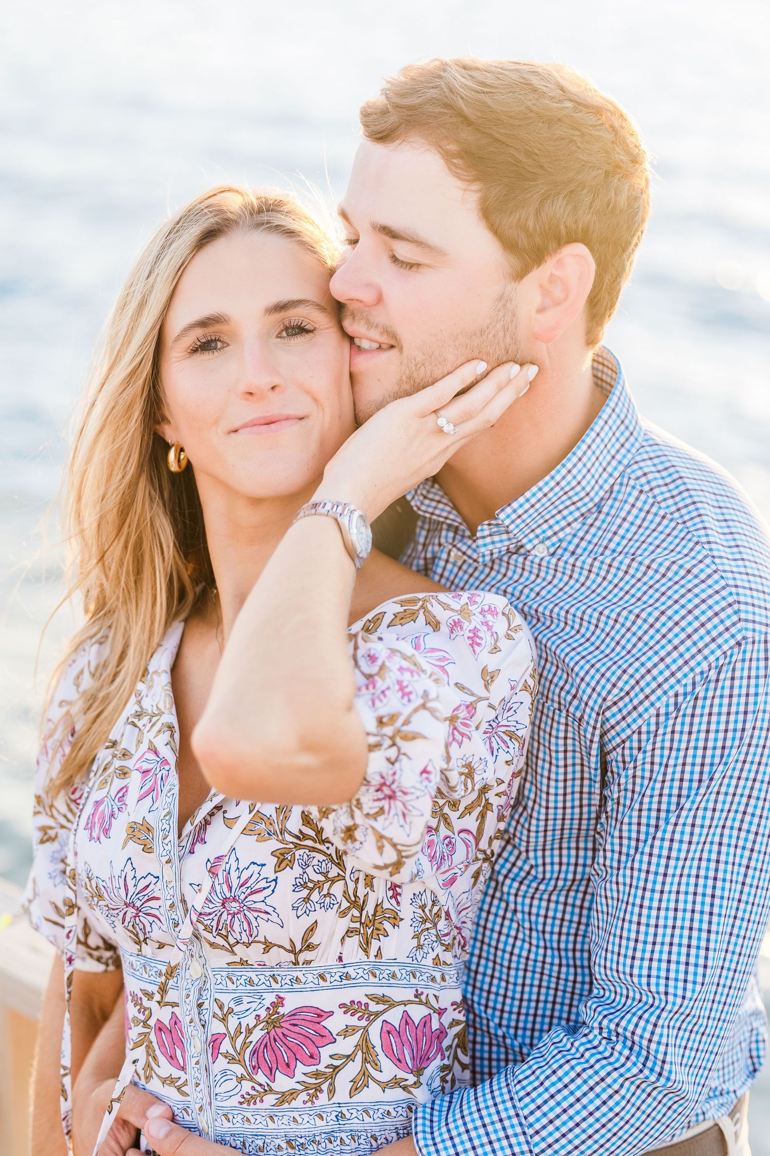 A tender embrace captured in warm sunlight on a coastal boardwalk.