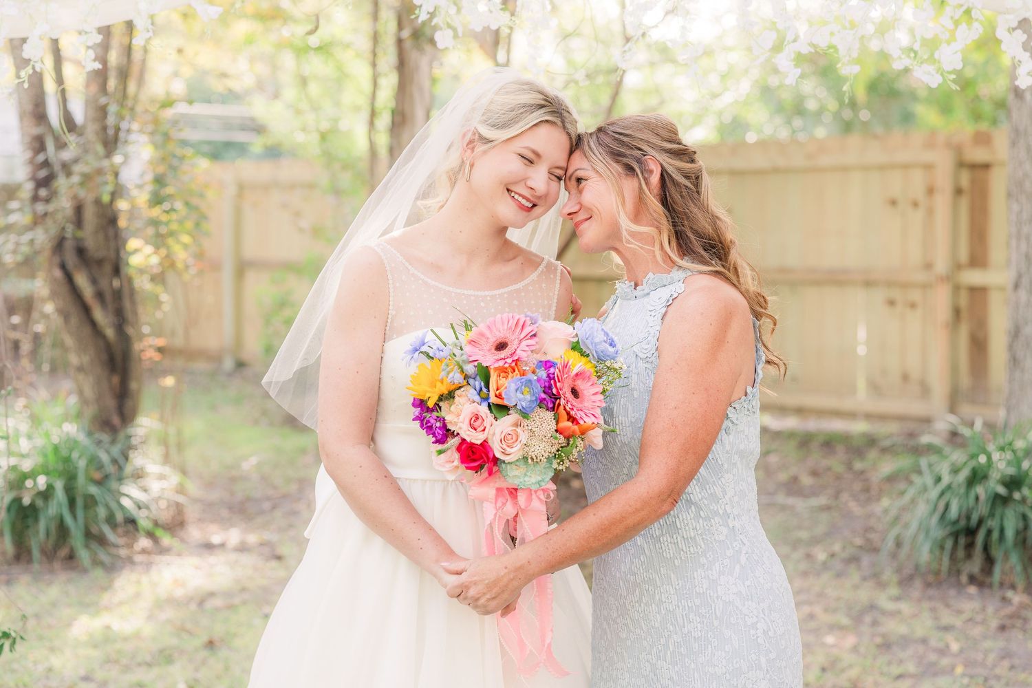 Wedding party members share candid moments while holding vibrant bouquets outdoors wedding groom bride wilmington photographer light and air