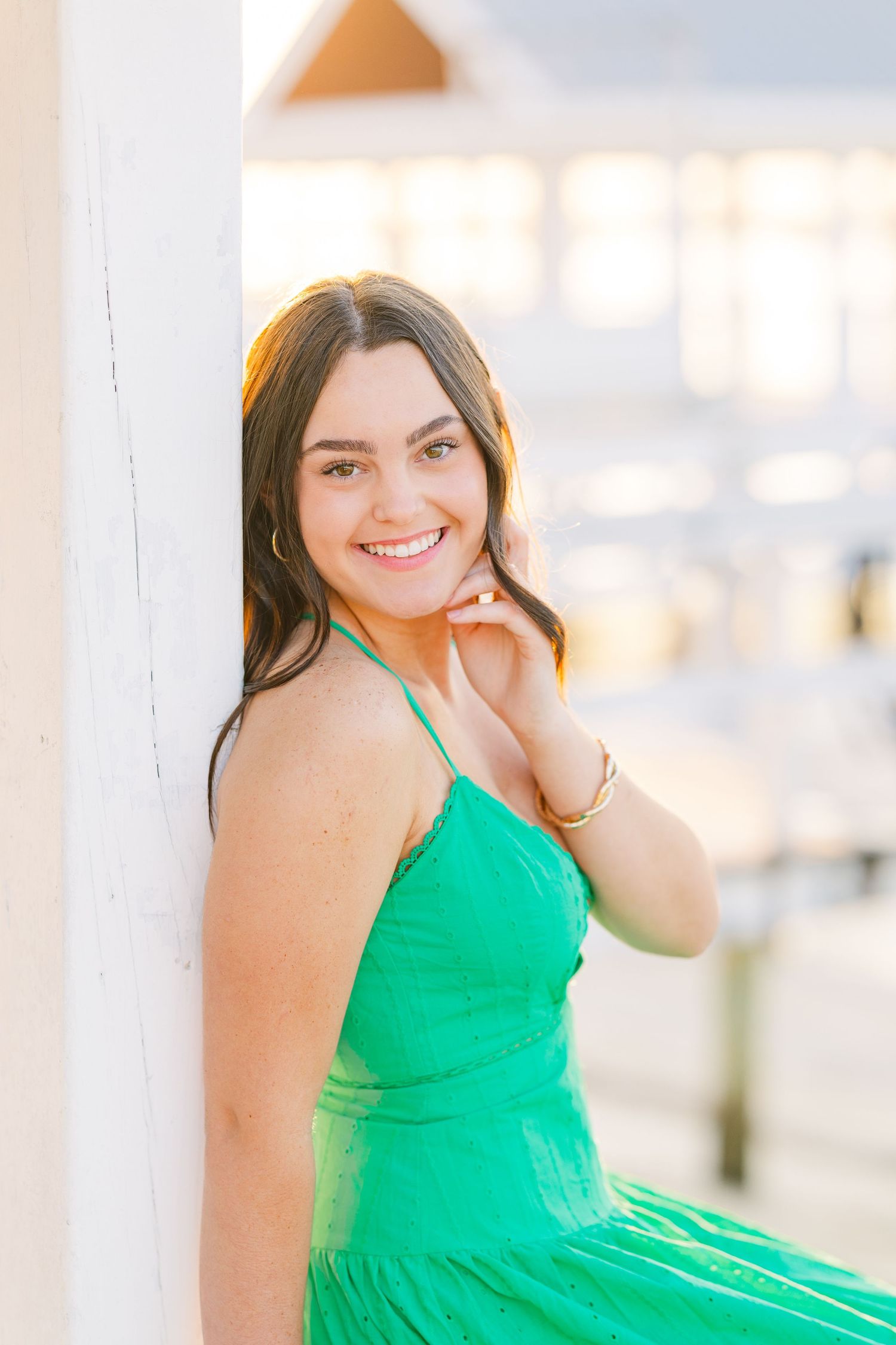 A vibrant green halter dress creates a striking contrast against a white coastal backdrop.