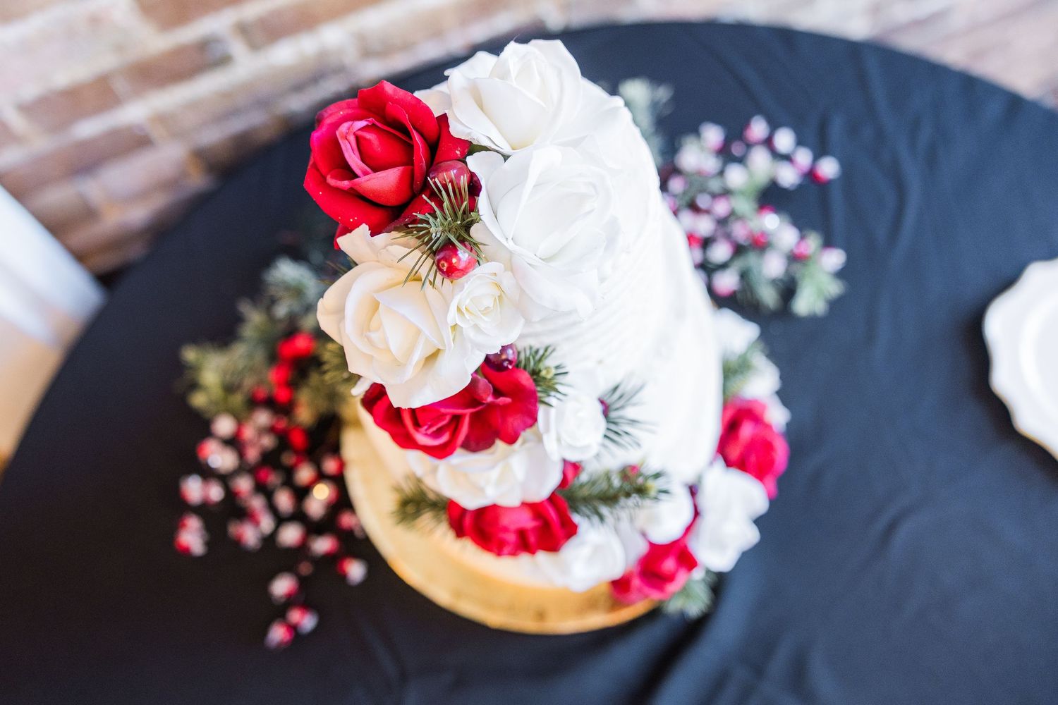 White wedding cake decorated with red and cream roses on a black slate platter wedding groom bride wilmington North Carolina photographer