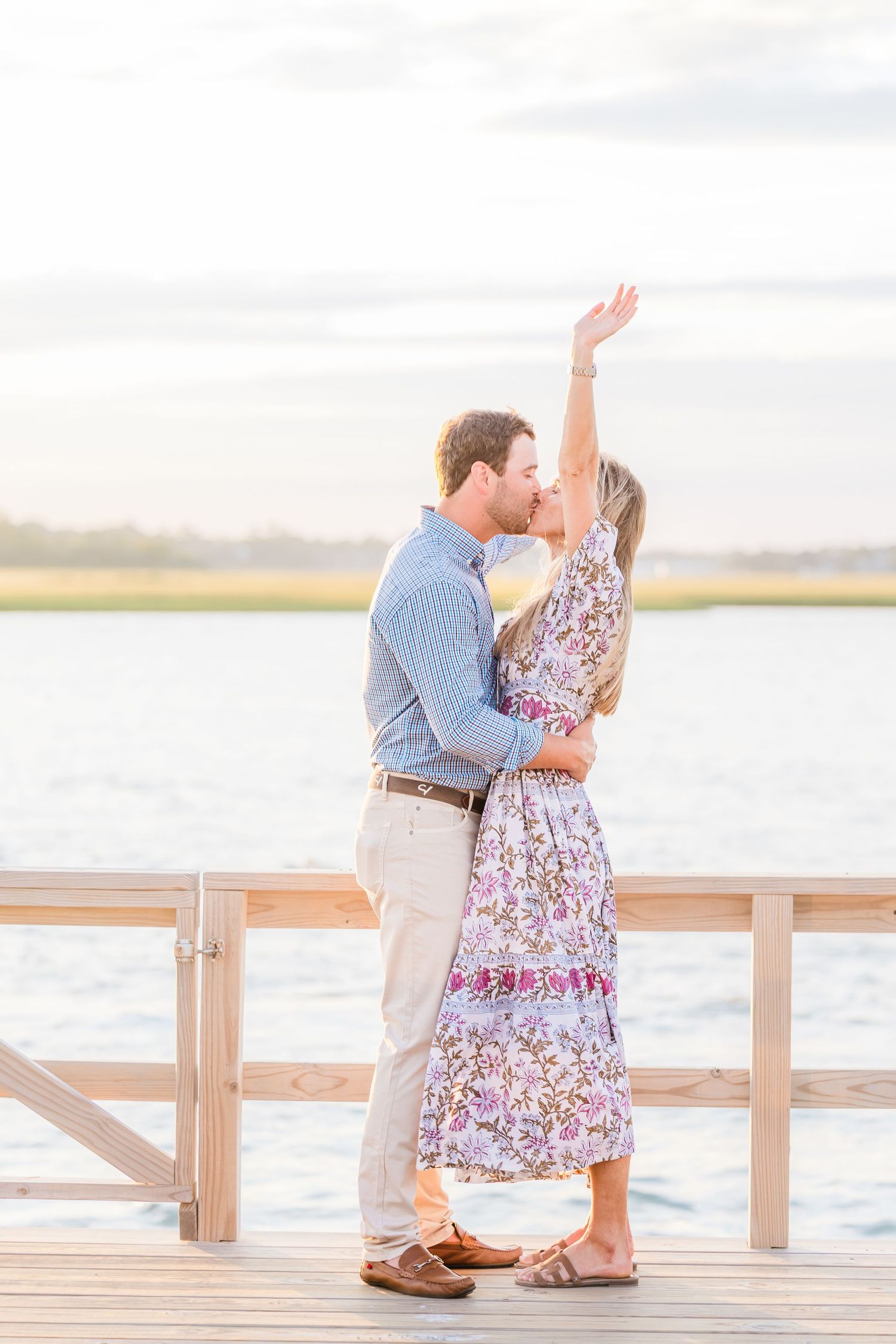 A surprise proposal moment captured on a waterfront dock during golden hour.