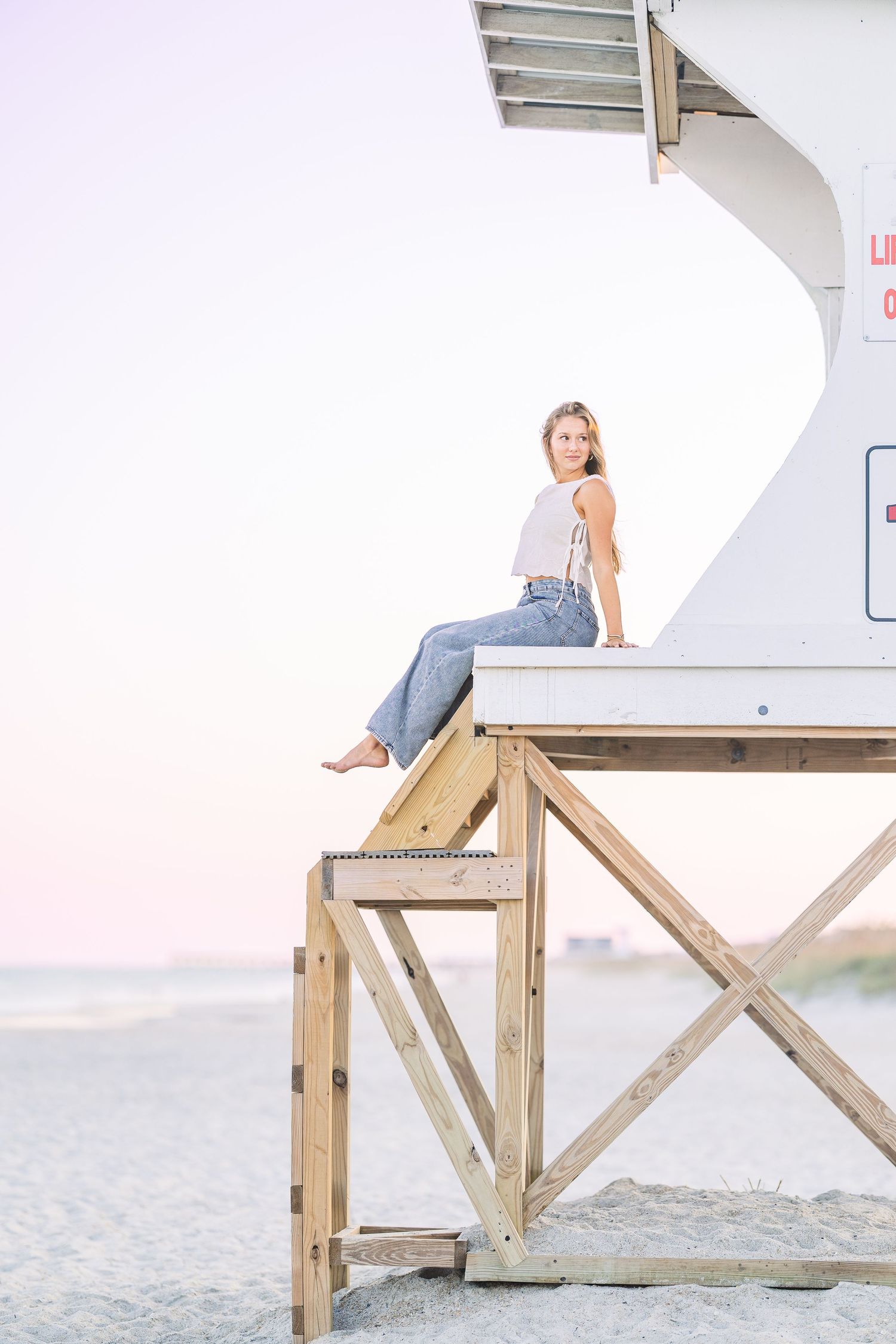 Lifestyle portraits on wooden lifeguard stand at beach during golden hour.