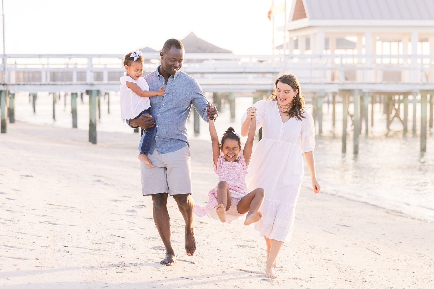 Family running and playing together on a sun-drenched beach.
