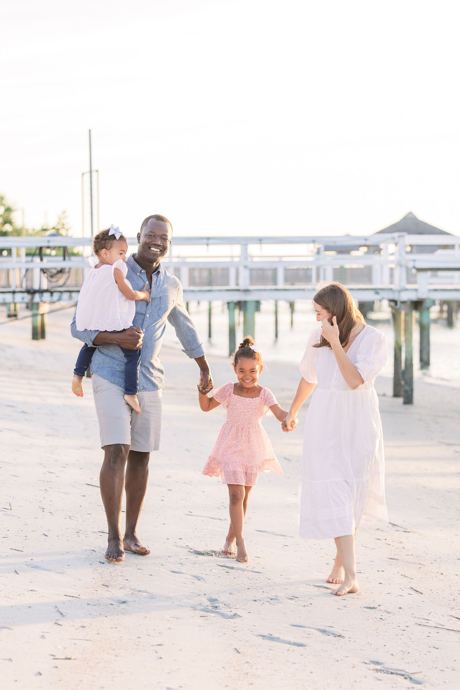 Candid family portrait showing joyful interactions on a sandy beach.