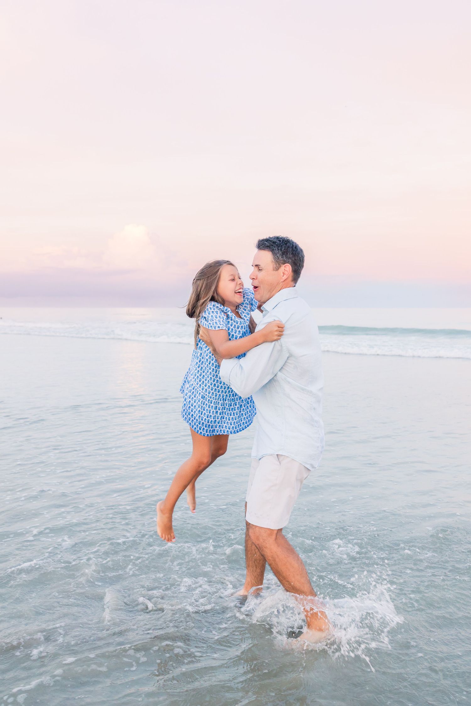 A joyful moment captured as family members play and splash in the ocean waves at sunset.