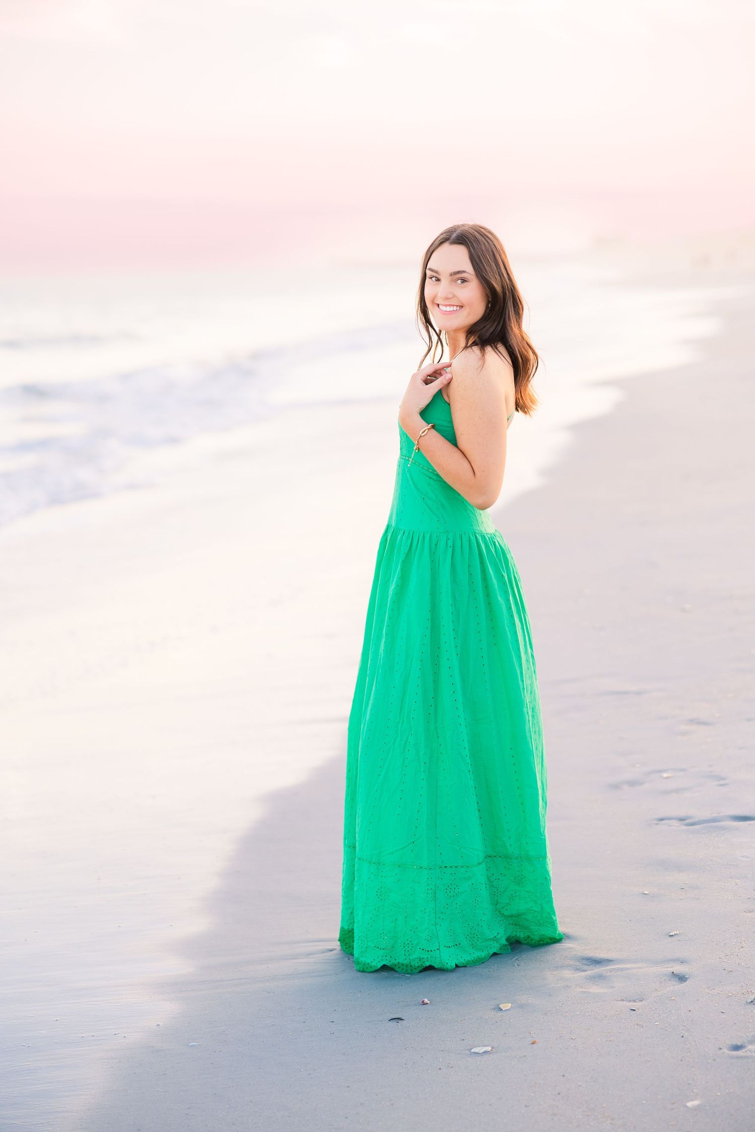 Dreamy beach portraits with an emerald green maxi dress against pastel sunset skies.