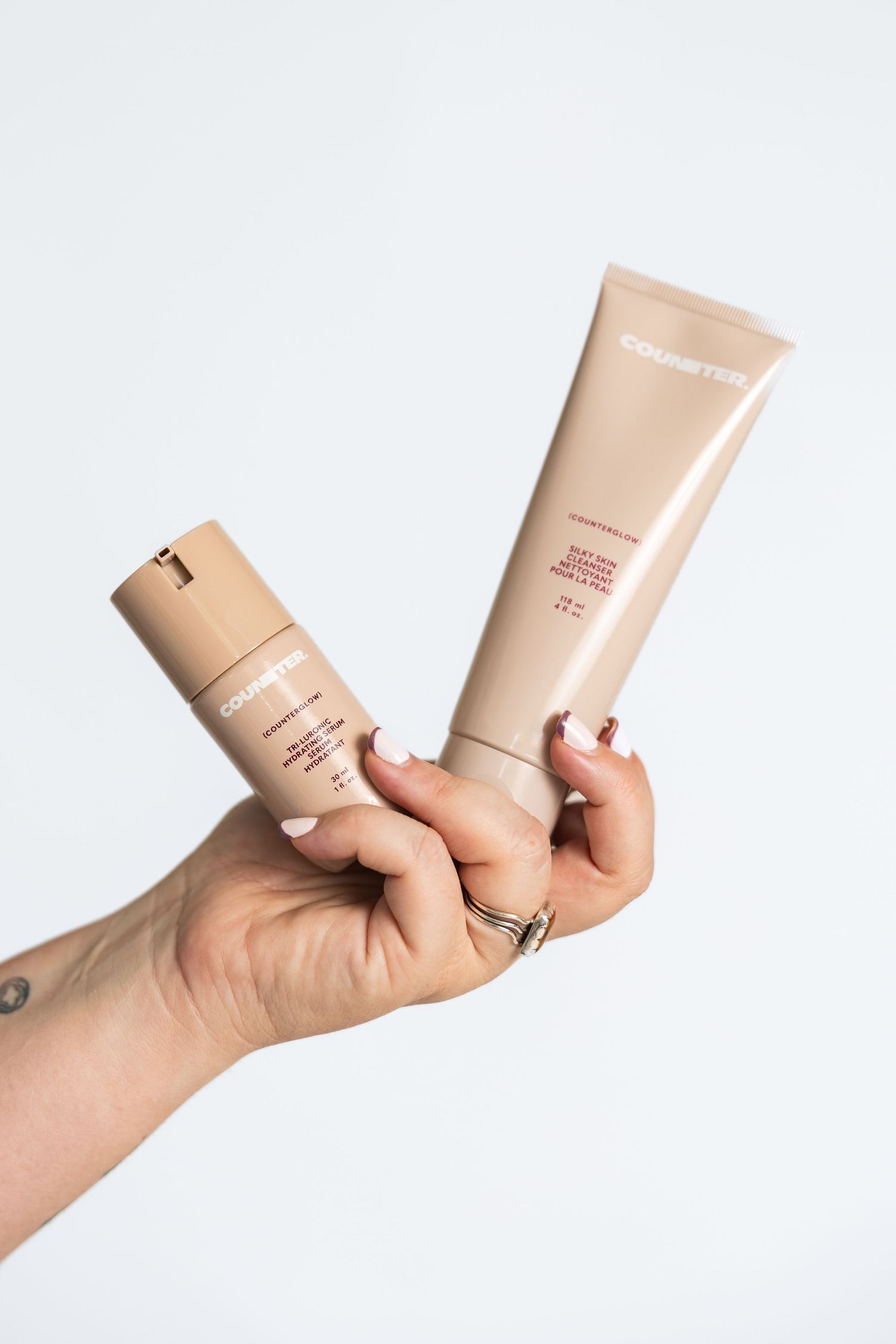 Hands demonstrating different angles of beige cosmetic product packaging.