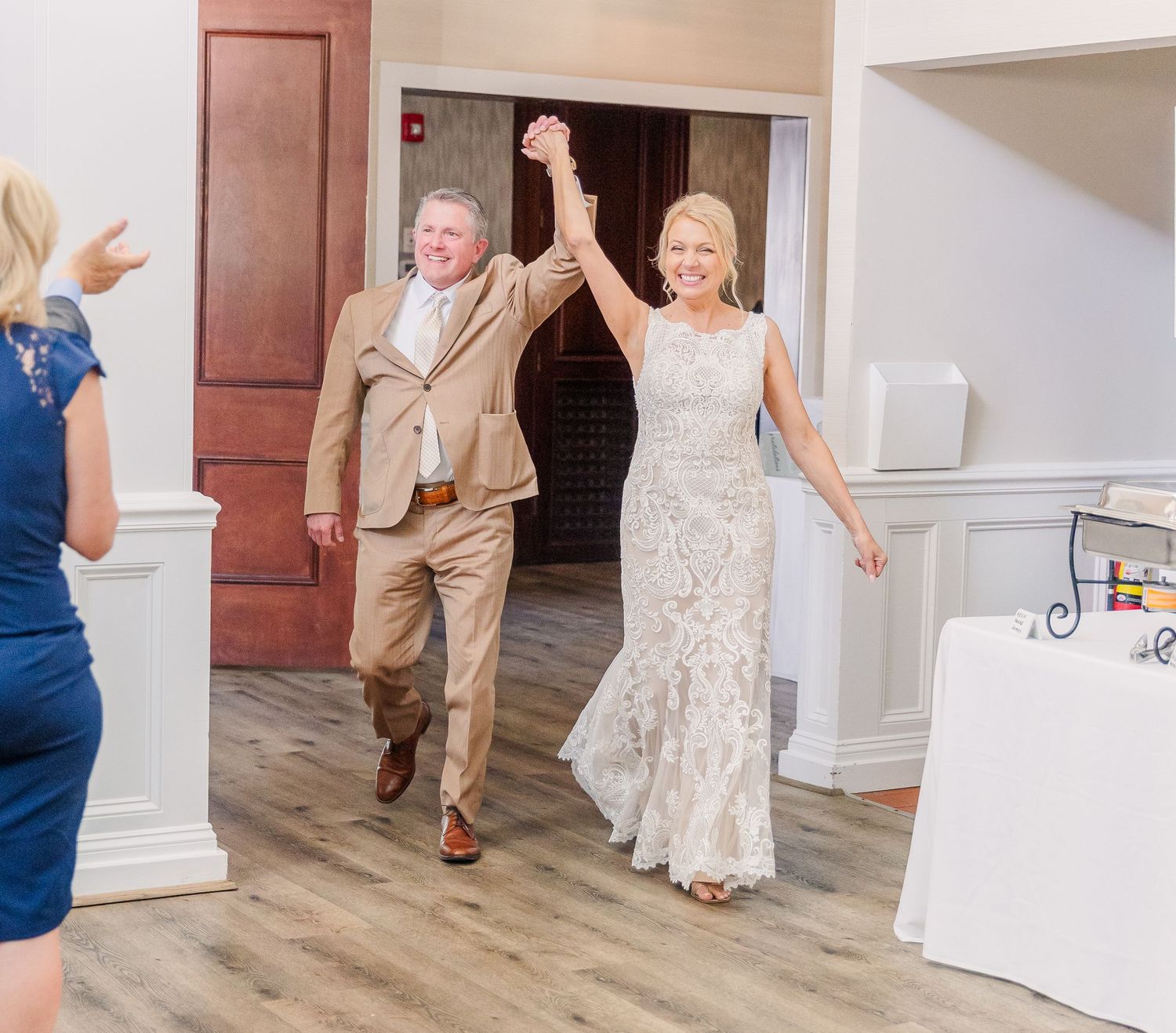 Wedding guests dancing and celebrating in a bright indoor reception venue.