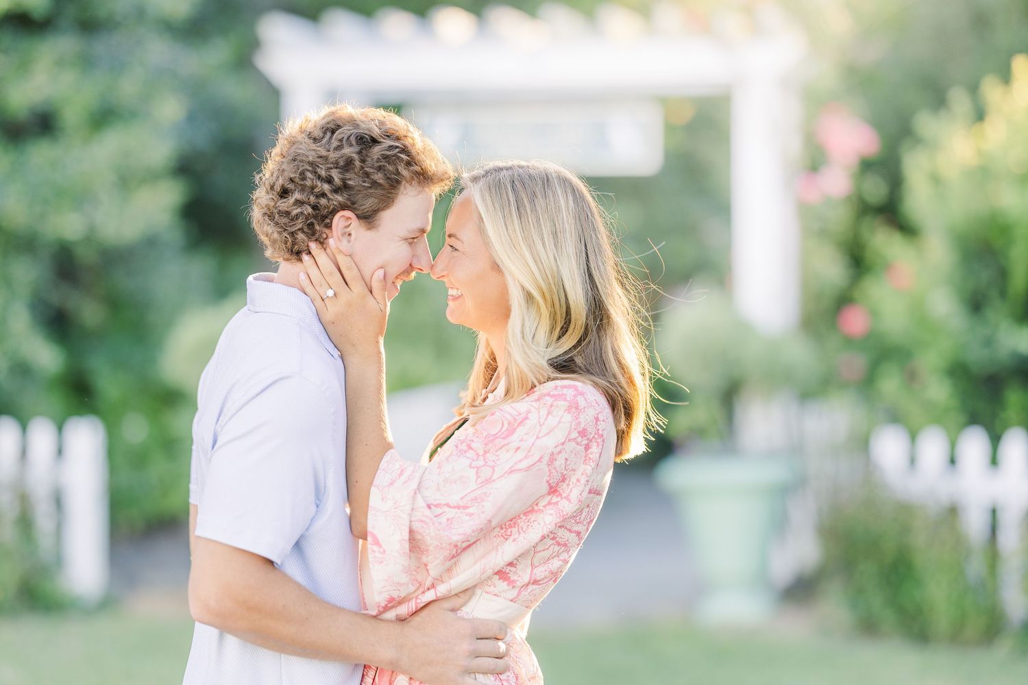 Candid moments captured between a couple in a garden with white picket fence.