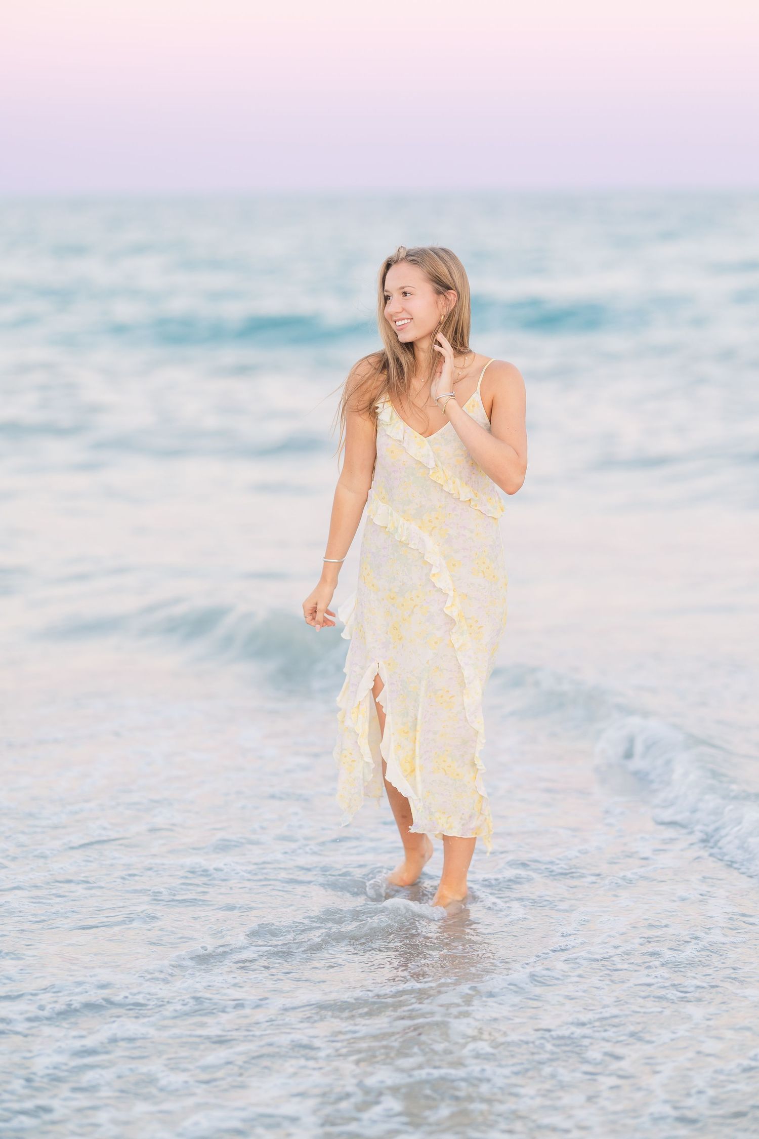 Playful movement shots in yellow dress along ocean shoreline.