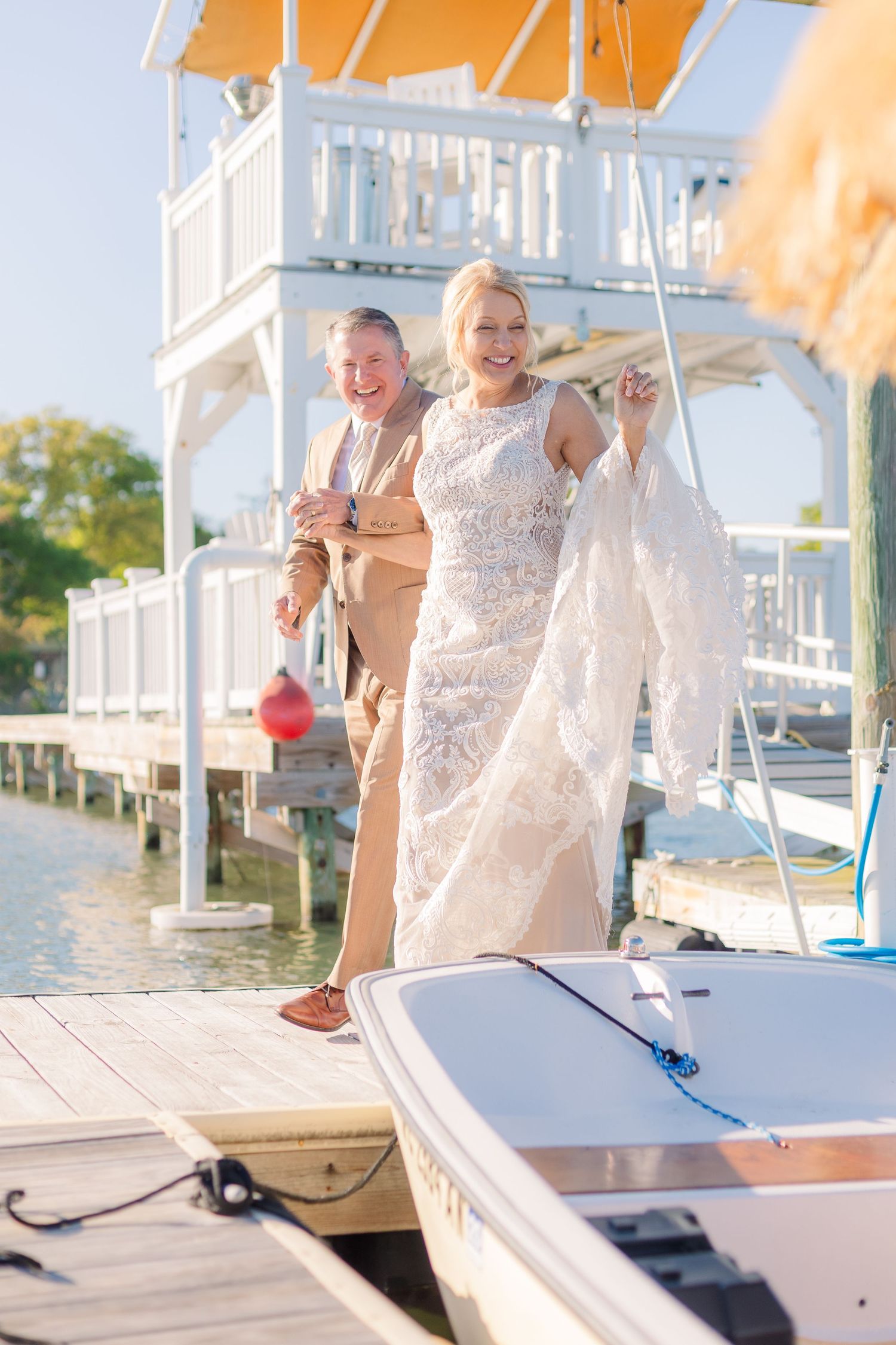 A couple celebrating on a boat dock with orange umbrellas and white railings.