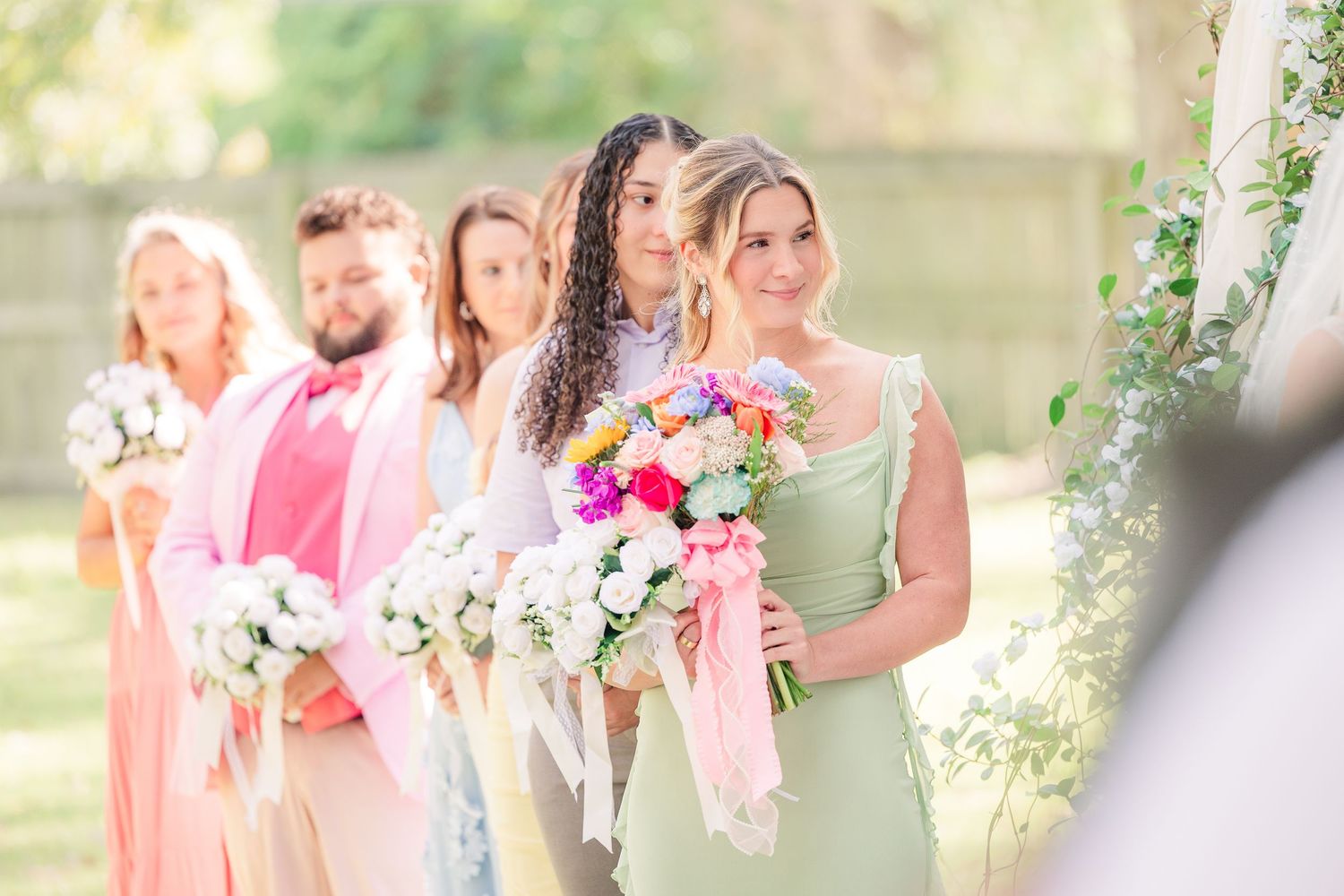 Wedding party members in pink dresses hold bouquets wedding groom bride wilmington photographer light and airy classic Wrightsville Beach