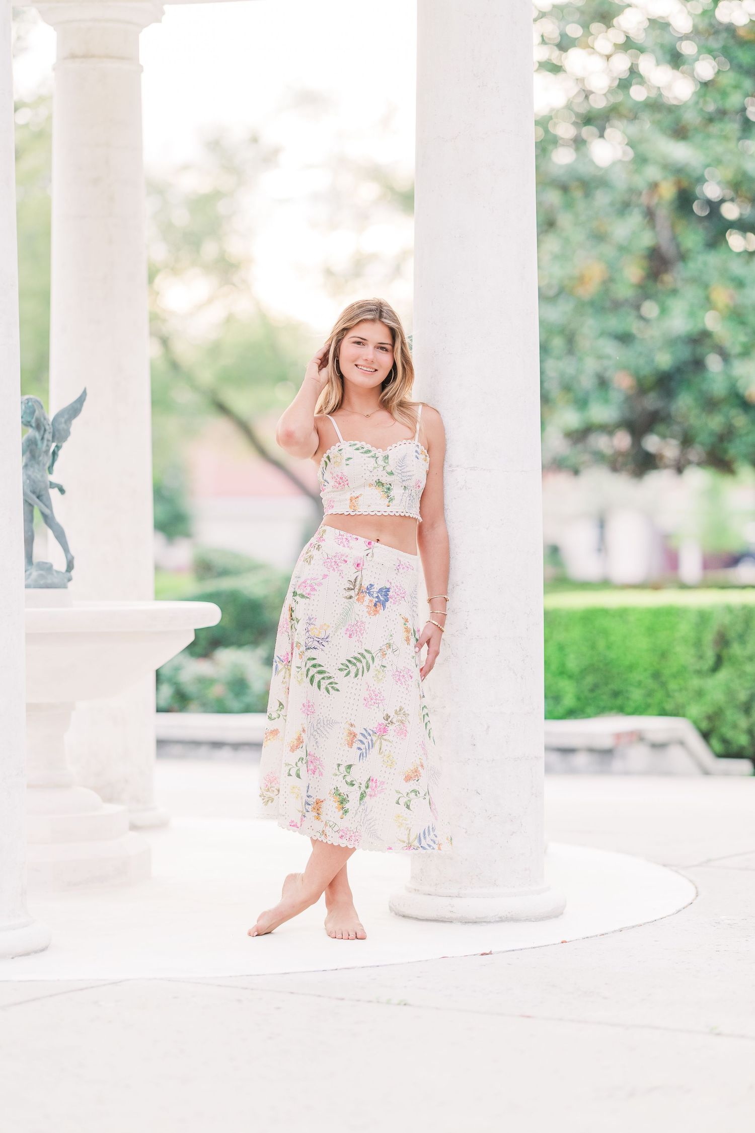 White floral dress photographed against classical columns in bright natural light.