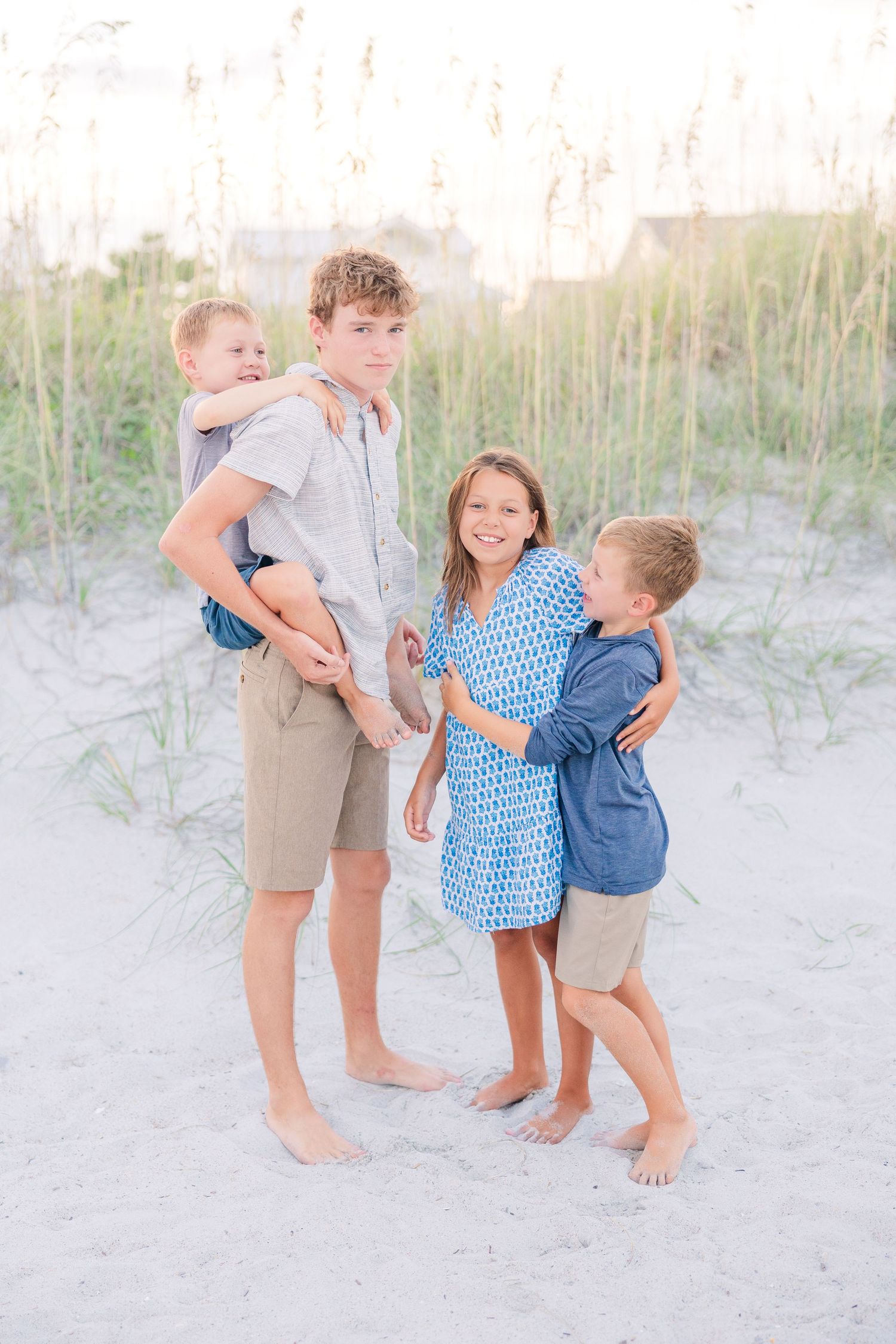 Kids share playful moments during a family photoshoot on beach dunes.