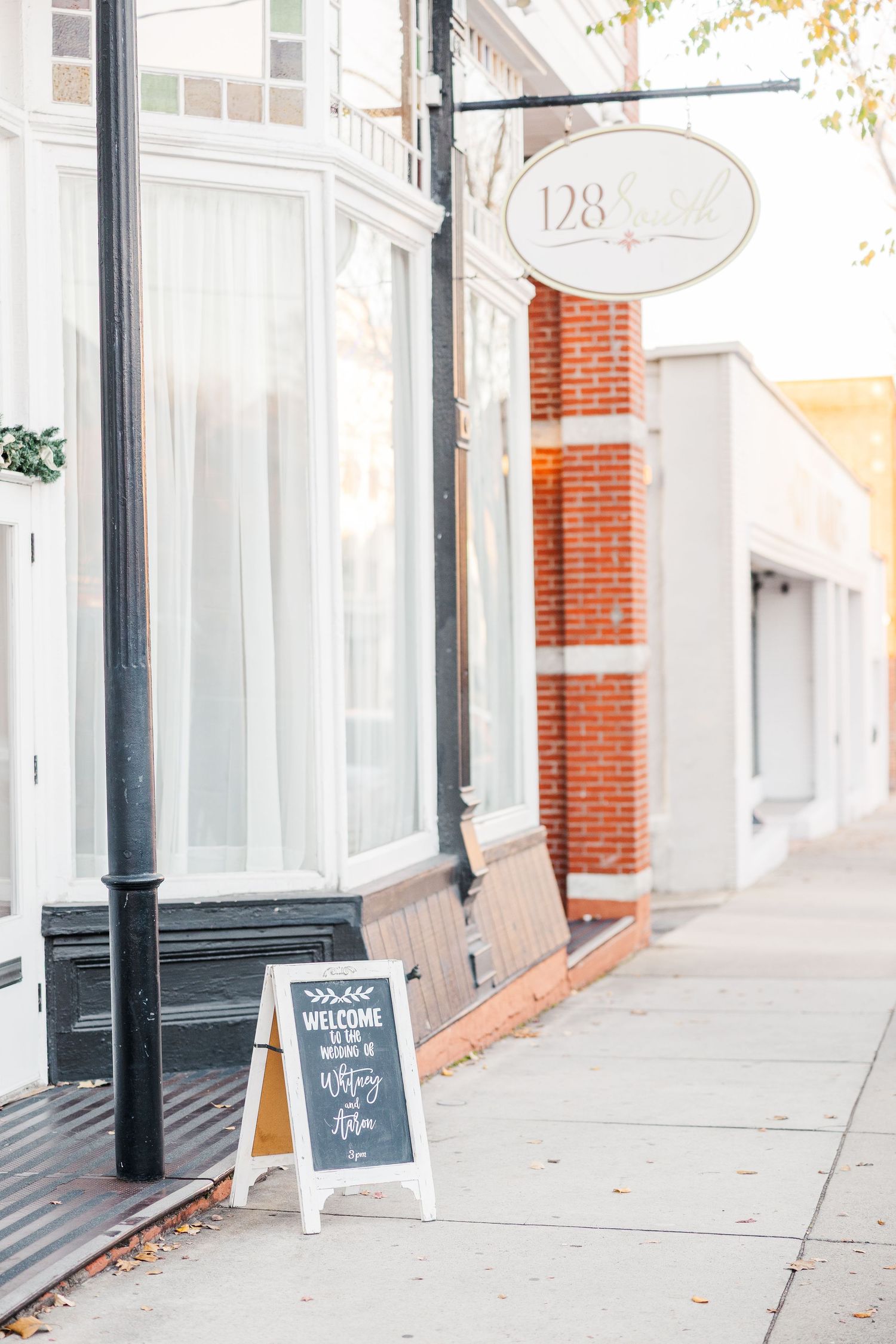 Clean white storefront with brick accents and welcome sign on sidewalk.