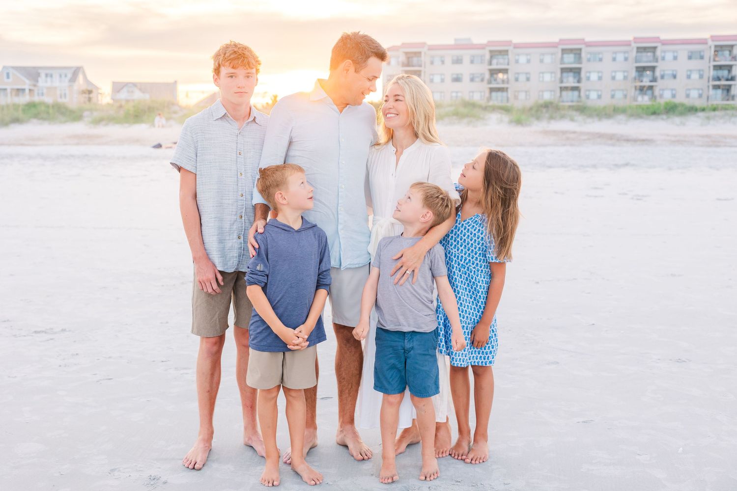 Family group photo at beach during sunset with condos in background.