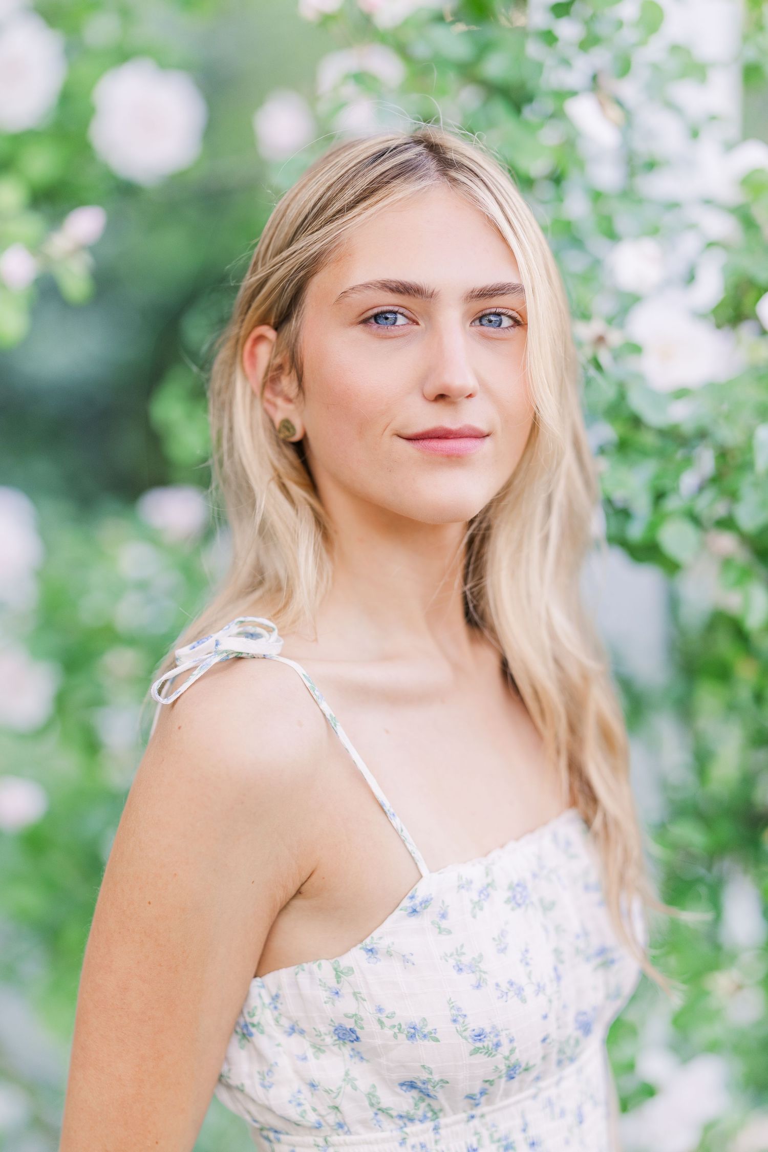 Soft springtime portrait with blooming white flowers in the background.