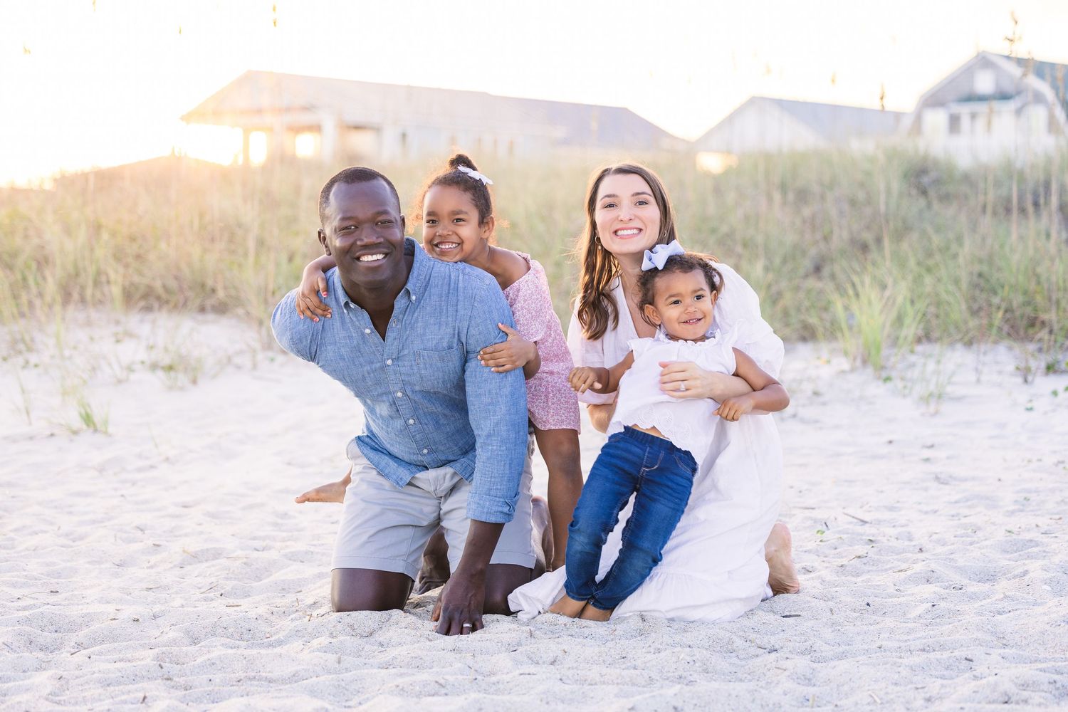 Natural family portraits taken on sandy dunes with warm evening sunlight.
