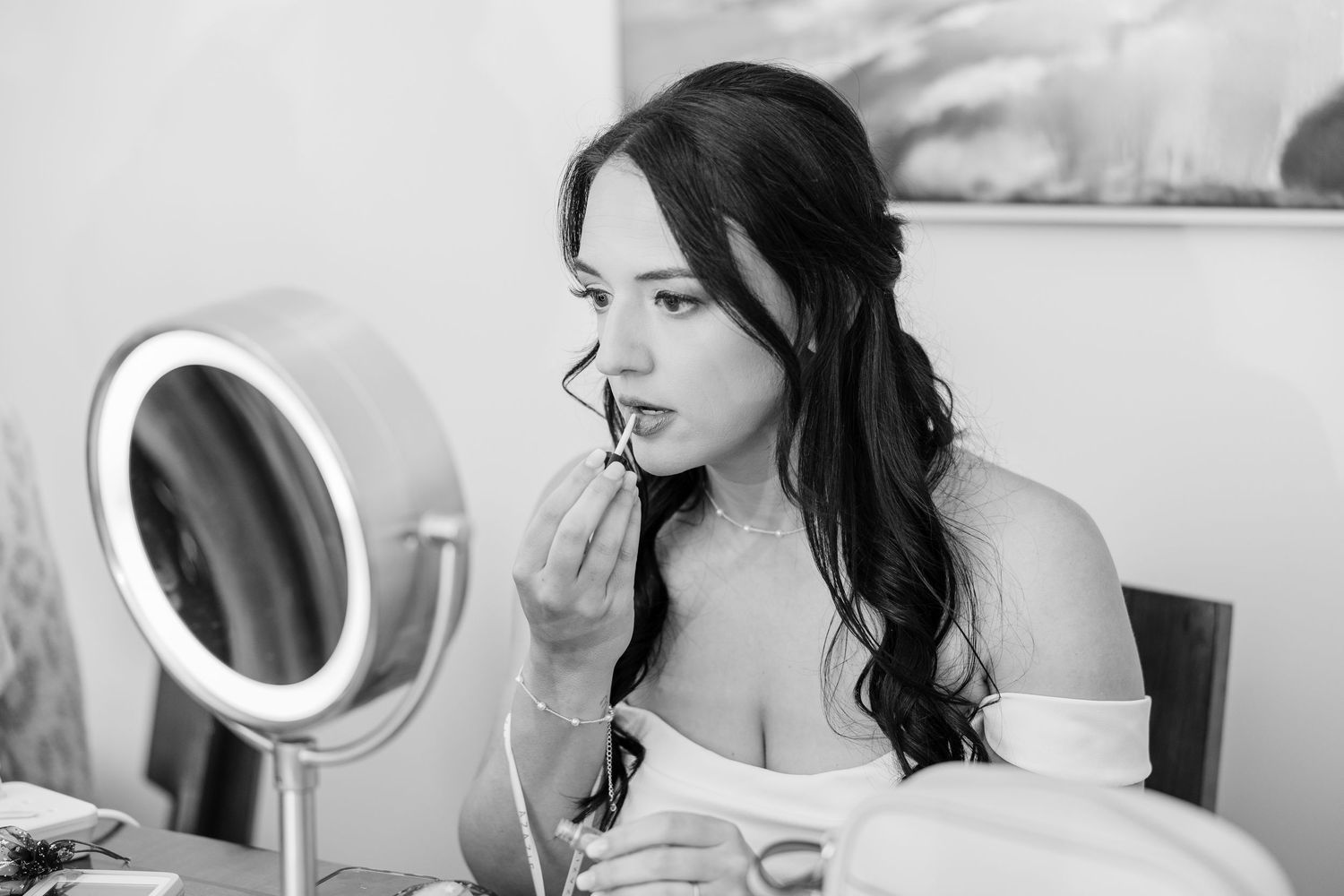 Black and white portrait of bride applying lipstick in front of makeup mirror wedding groom bride lake Gaston photographer light airy