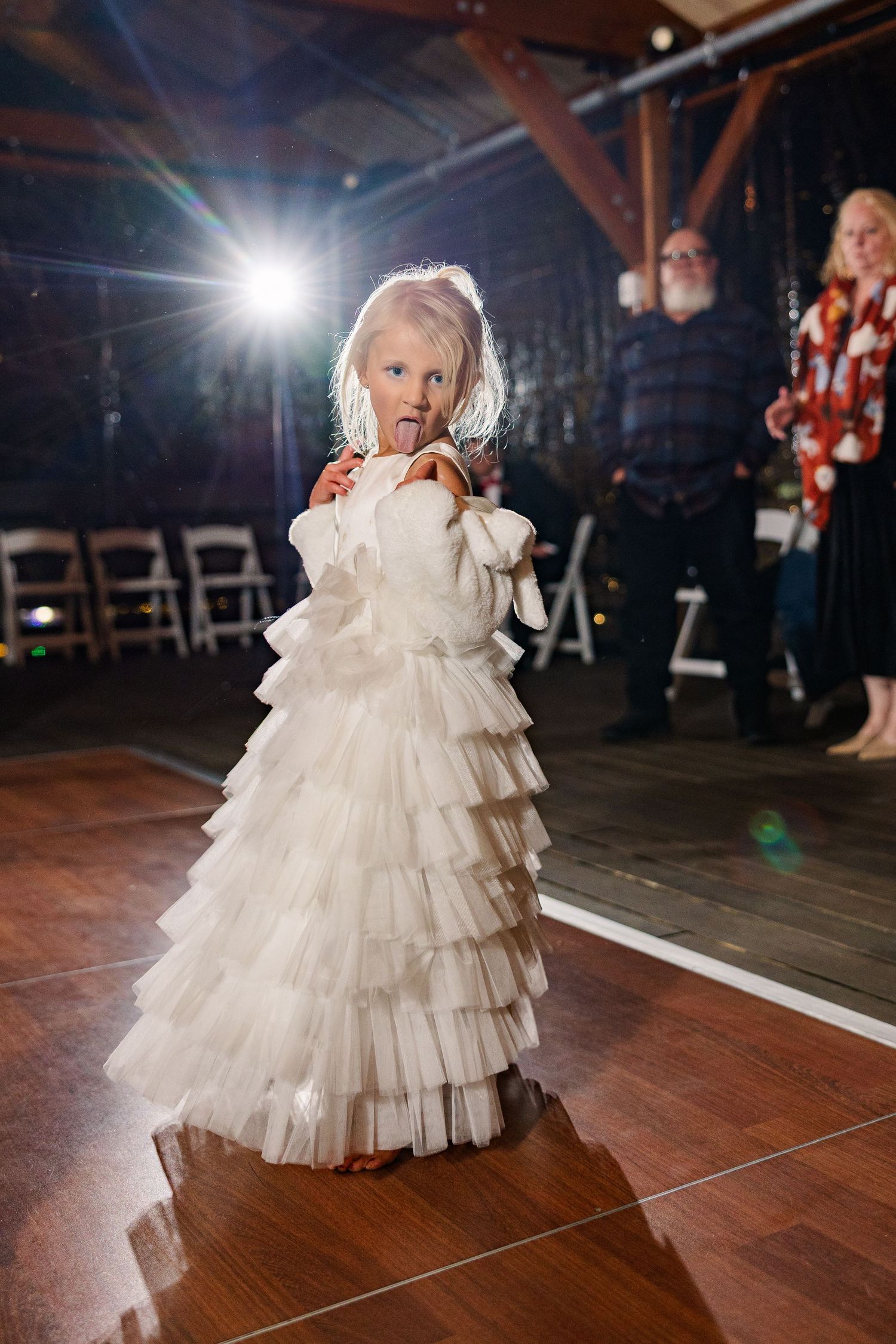 A young attendant in a white tiered dress poses on the dance floor at a wedding reception wedding groom bride wilmington North Carolina