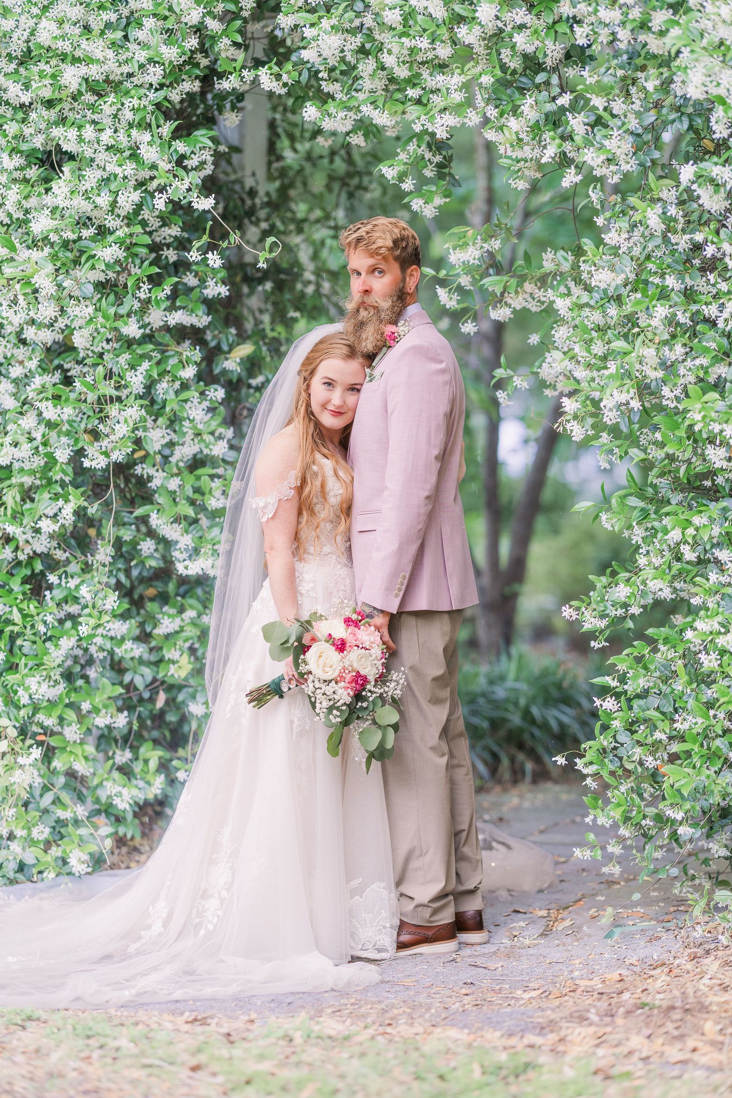 Spring wedding photography featuring soft pink and white tones under flowering tree branches in harborway gardens in Wrightsville Beach, nc