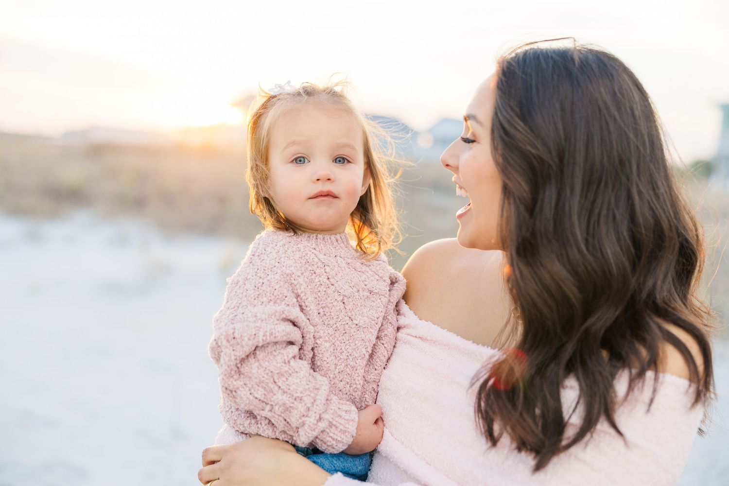 Intimate family portraits on a sandy beach with coordinated pastel outfits.