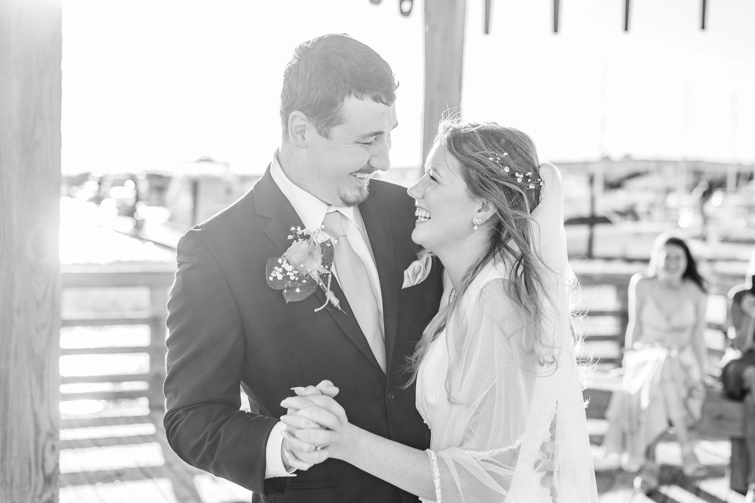 Newlyweds share tender moments during their first dance on an outdoor wooden pier southport elopement wedding bride groom light and airy