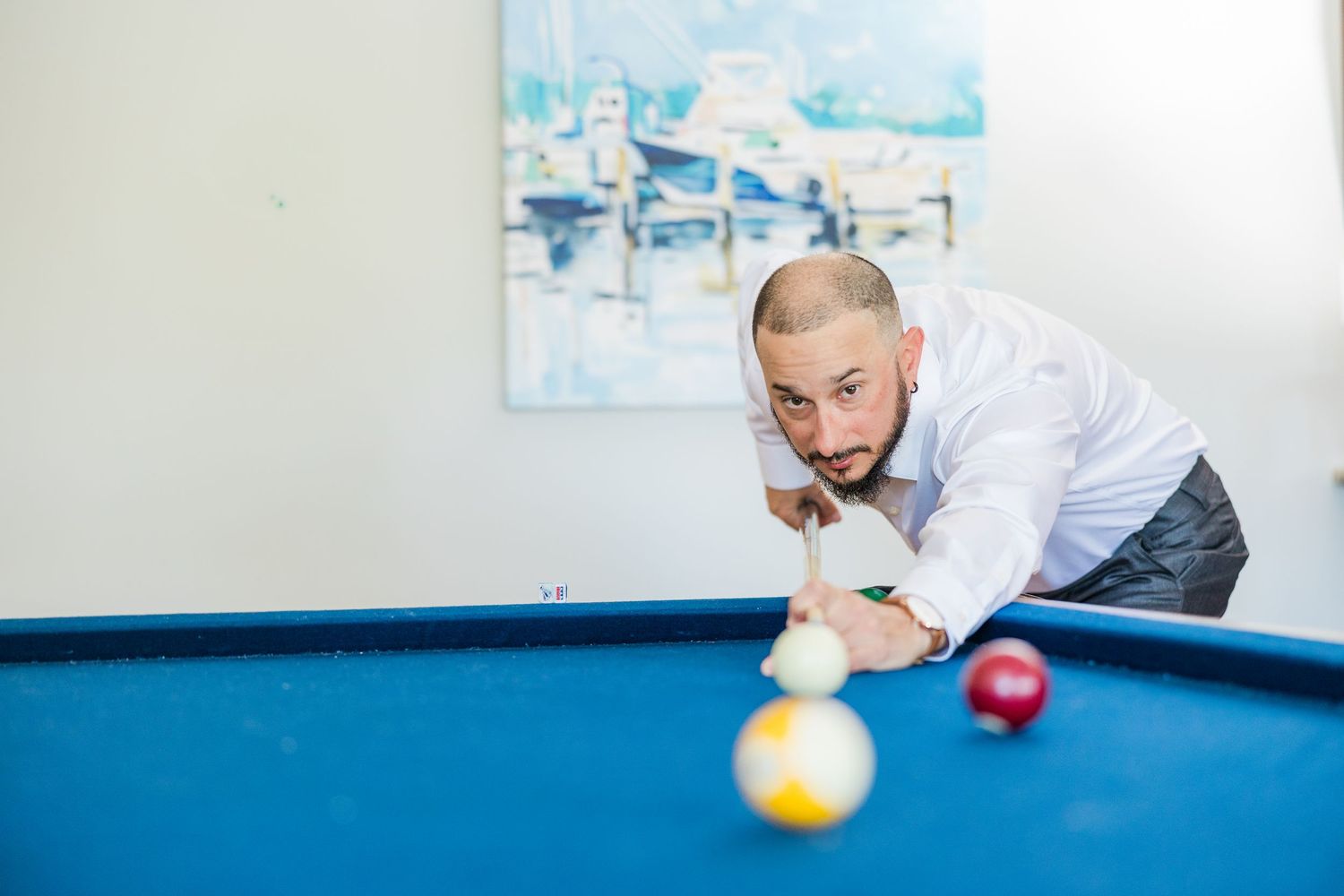 People playing pool on a blue felt table in a bright room wedding groom bride lake Gaston photographer light airy