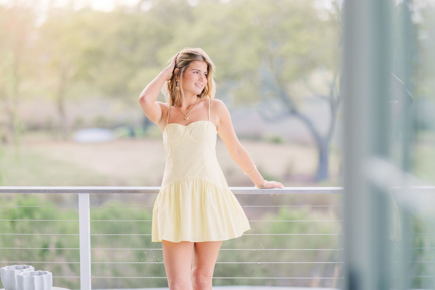 A light yellow sundress is worn on a sunny deck with white railings and natural lighting.