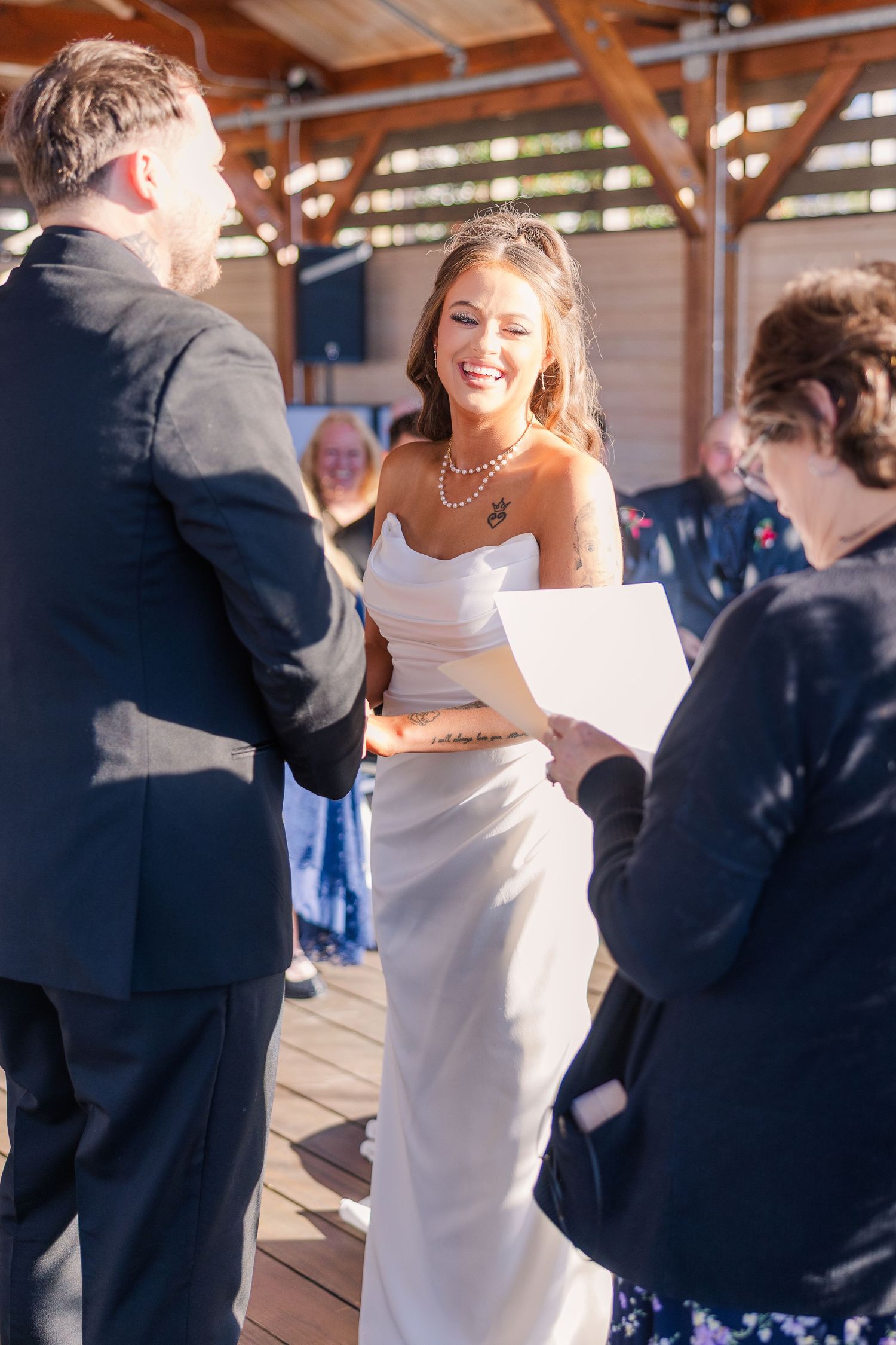 Wedding ceremony on a wooden deck with guests gathered to witness the celebration.
