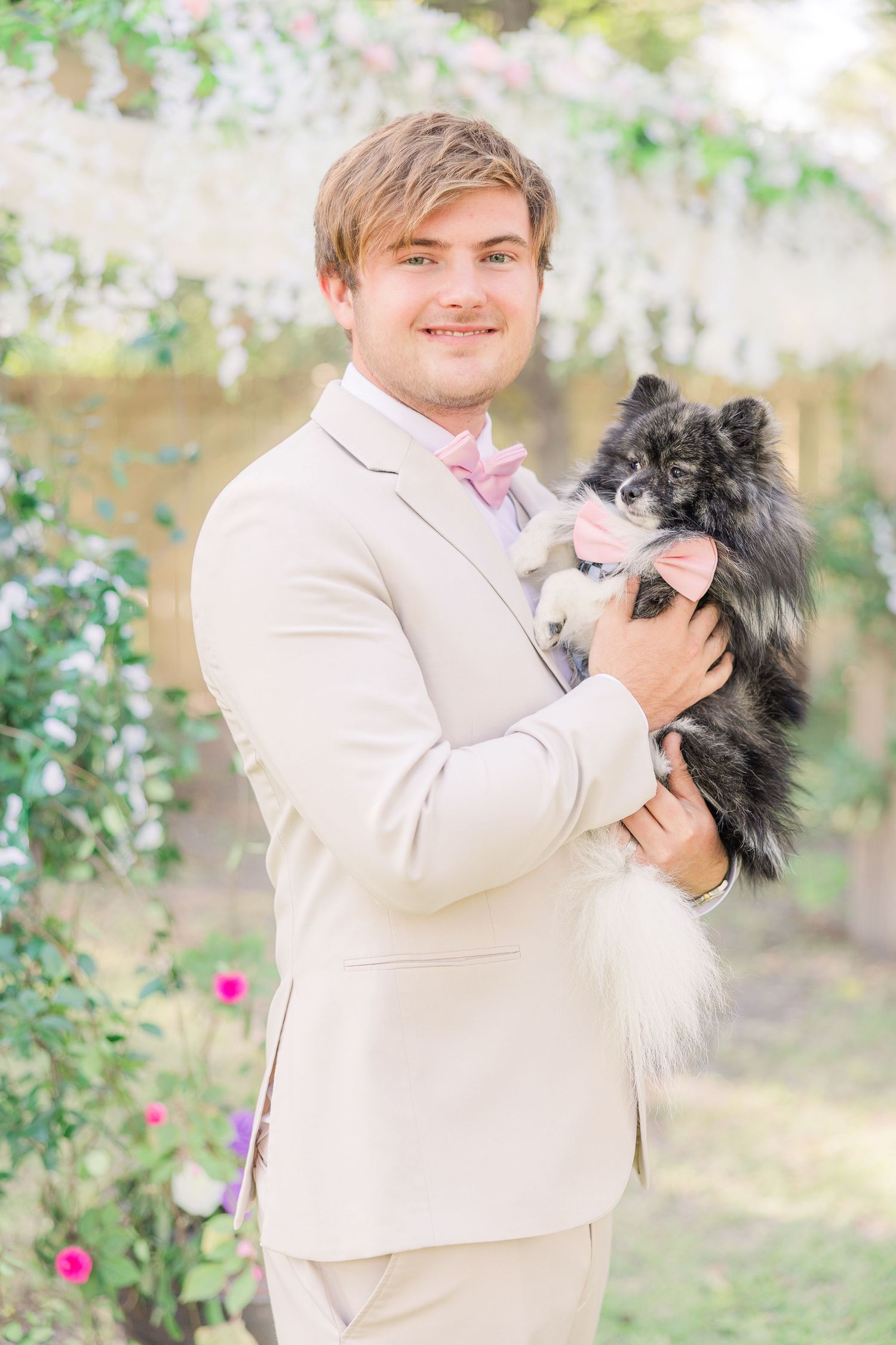 Groom in beige suit holds small black and white dog wedding groom bride wilmington photographer light and airy classic Wrightsville Beach