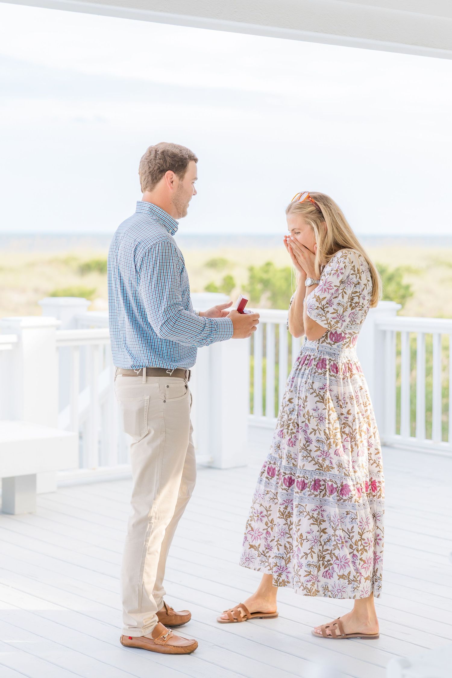 A surprise proposal sequence on a white coastal deck with ocean views.