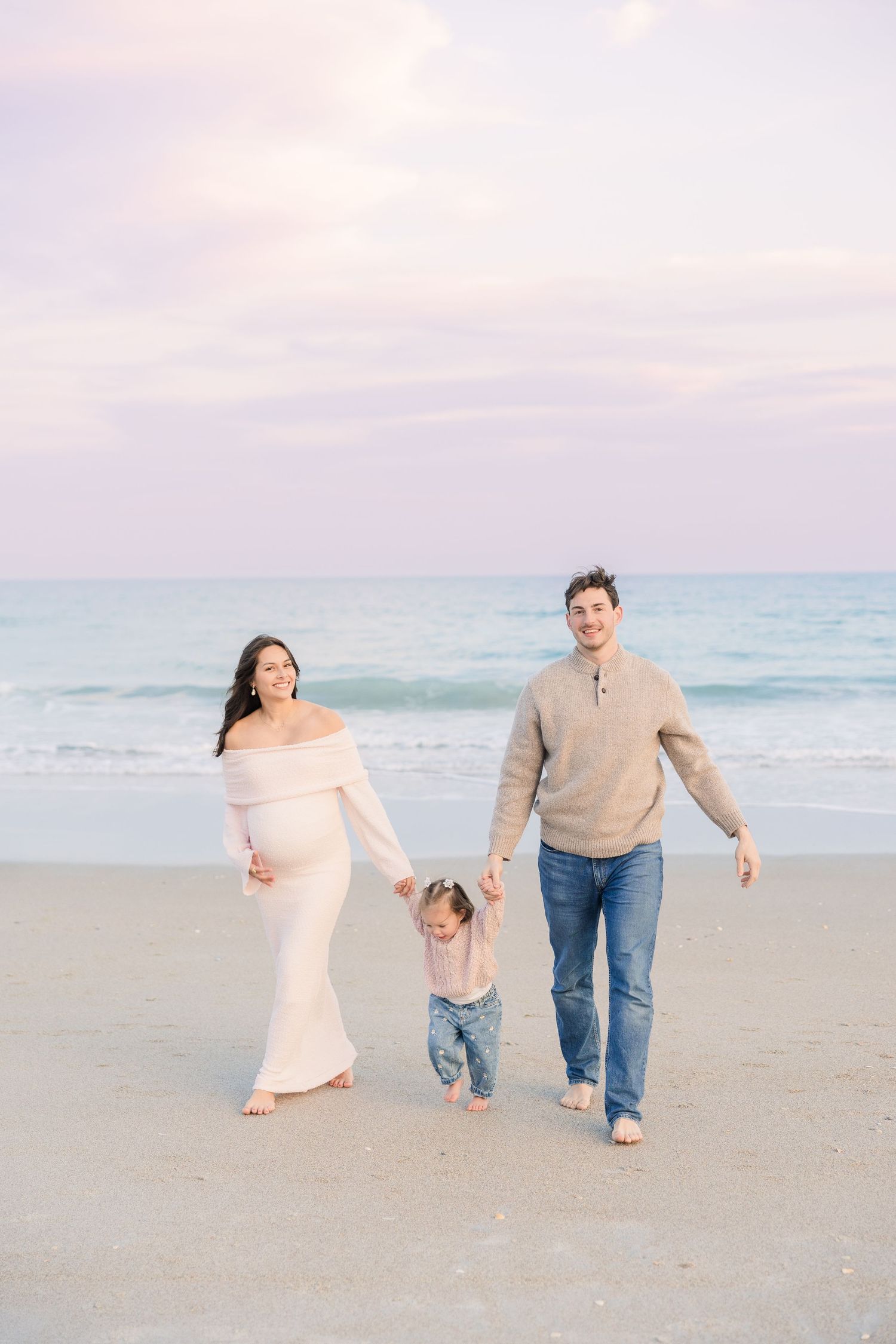 Playful family beach session with coordinated outfits in soft pastel colors.